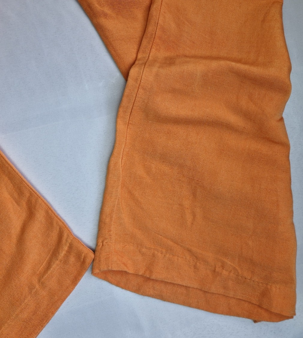 Close-up of the hem of orange wide-leg linen blend trousers from H&M.