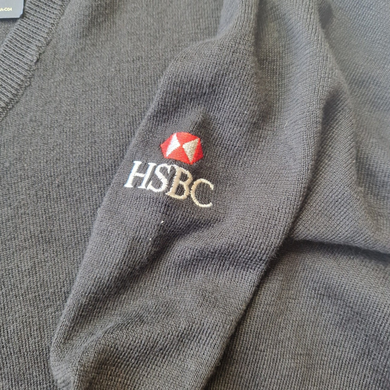 A black Ralph Lauren V-neck cotton sweater featuring an embroidered HSBC logo on the sleeve.
