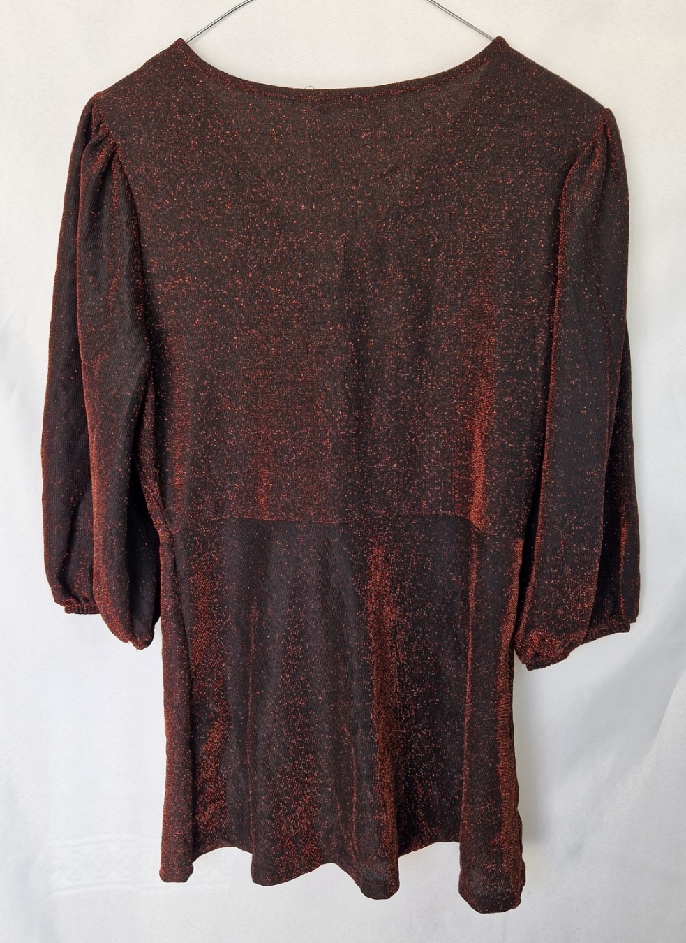 A maroon long-sleeve top with a glitter finish, V-neckline, and voluminous sleeves.