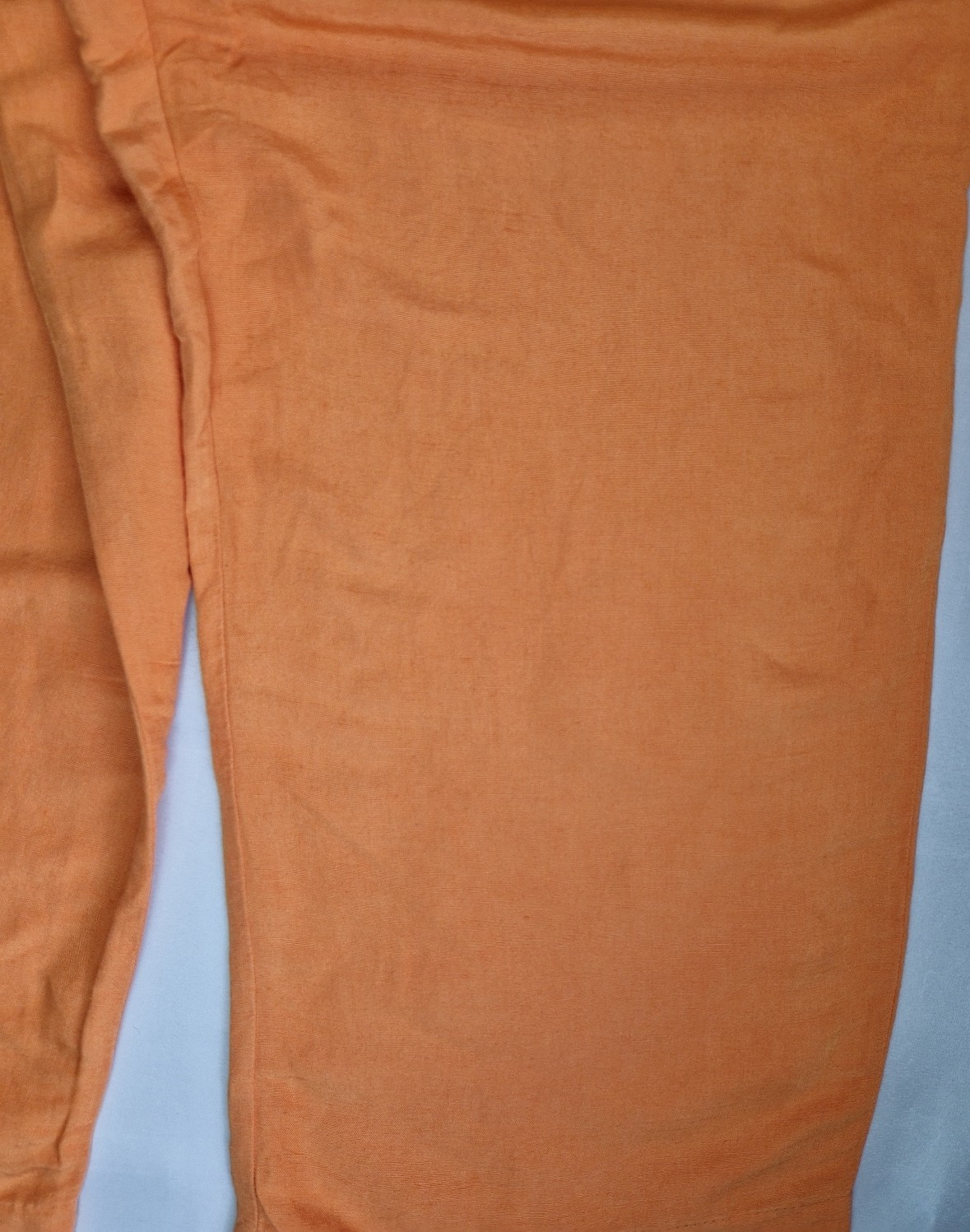A close-up of orange wide-leg jogger trousers made from a linen-blend fabric.