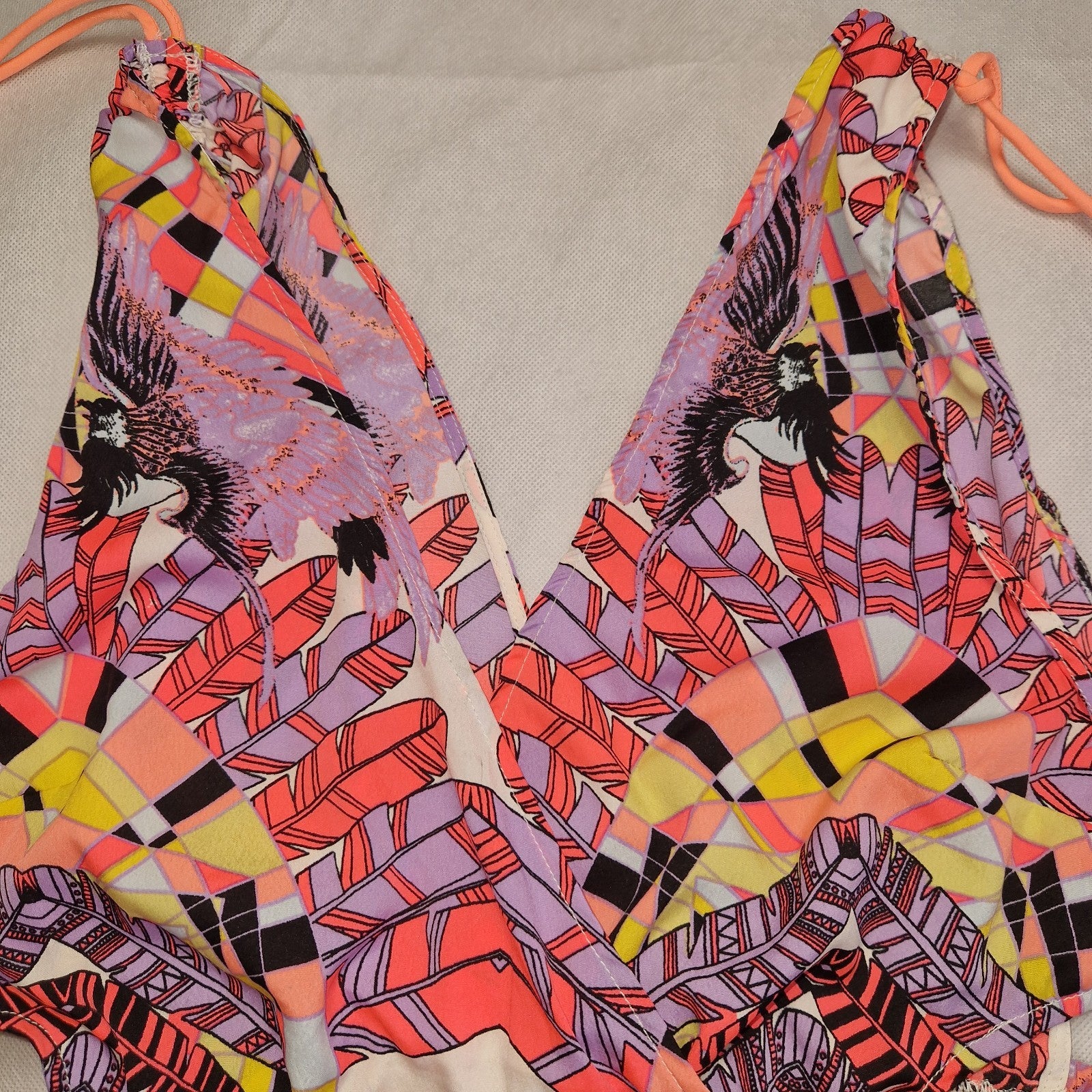 A multicoloured floral print playsuit with an off-the-shoulder neckline and tassel tie accents.