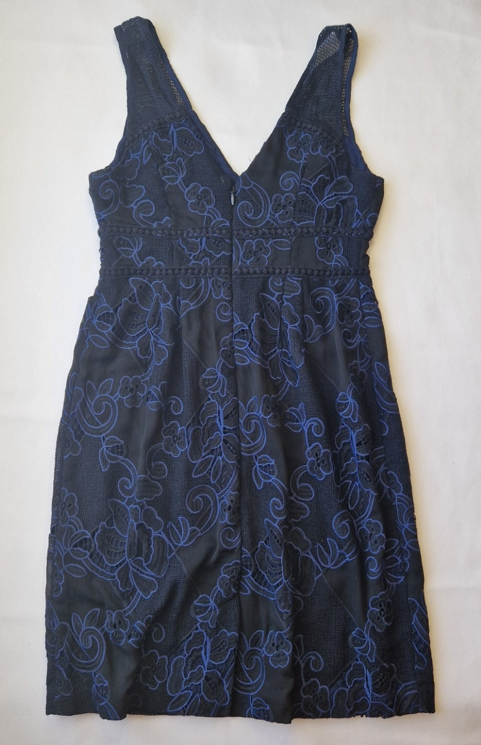 A black sleeveless knee-length dress featuring blue floral embroidery on lace fabric.