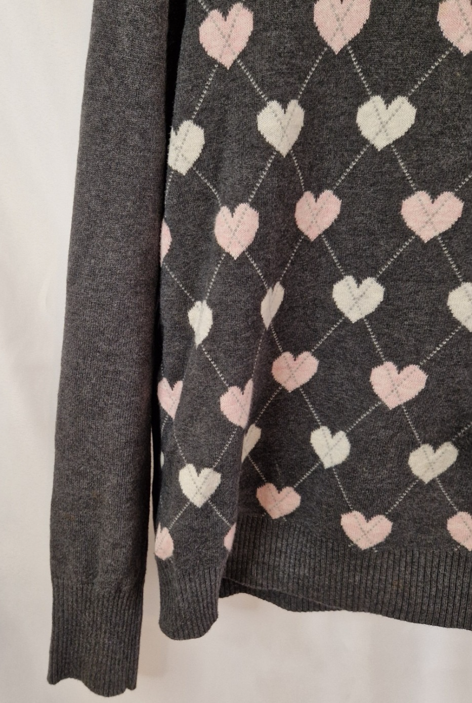 A grey Papaya long-sleeve jumper featuring a repeating white and pink heart argyle pattern.