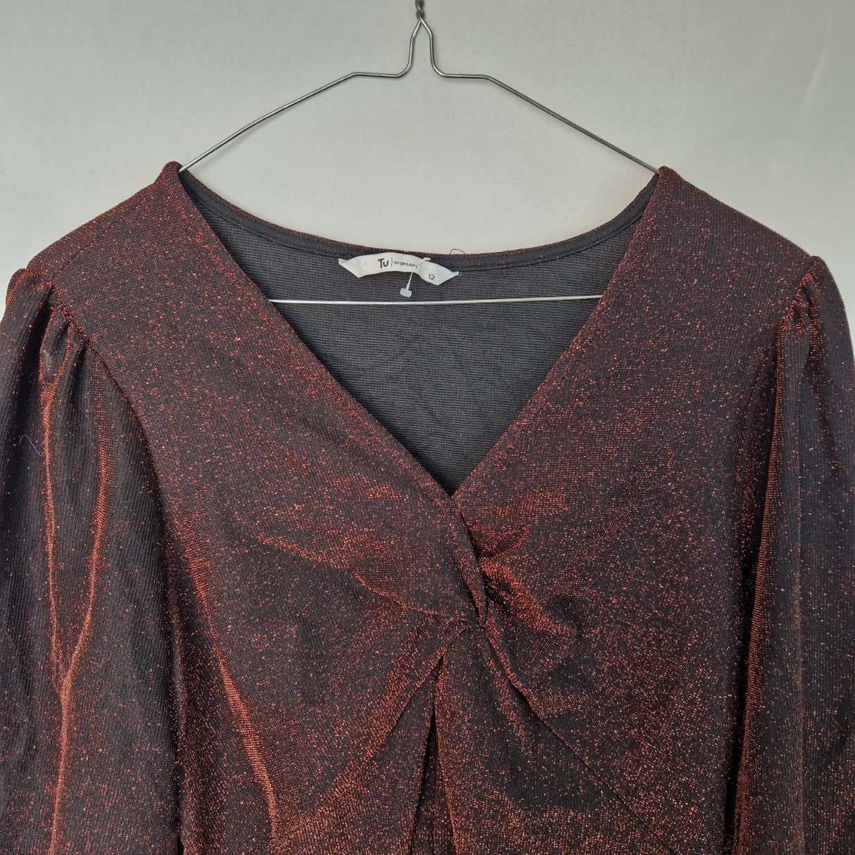 A maroon long-sleeve V-neck top with a glitter finish and a twist front detail.