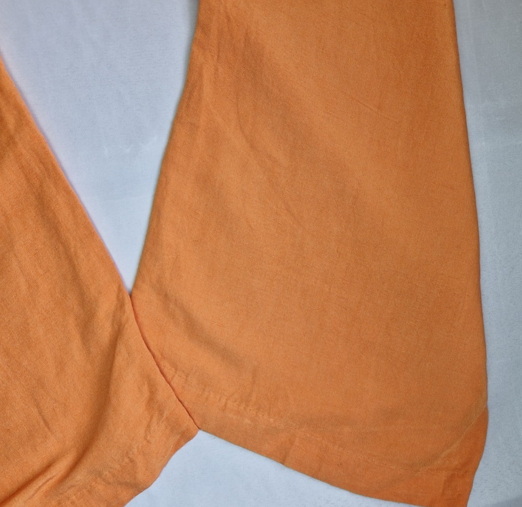 Close-up of the orange linen-blend fabric on the wide-leg hem of H&M trousers.