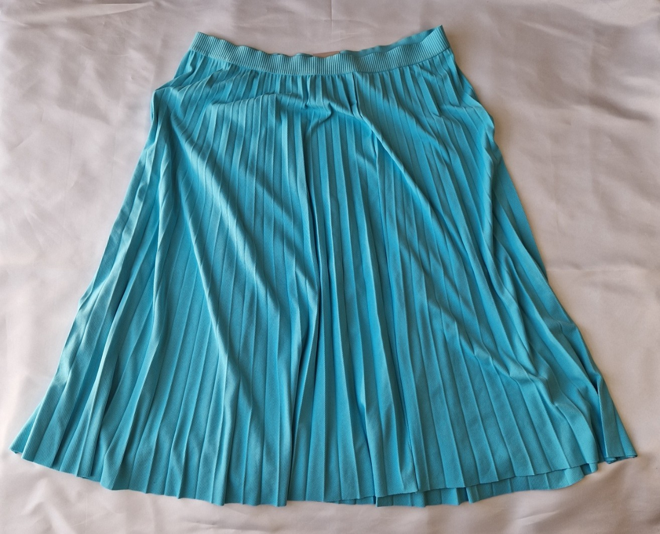 A turquoise pleated midi skirt with an elasticated waistband, laid flat on a white surface.