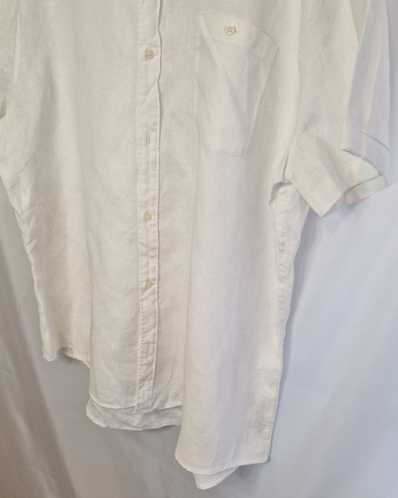 A white short-sleeved button-down shirt with a chest pocket and a subtle floral print.