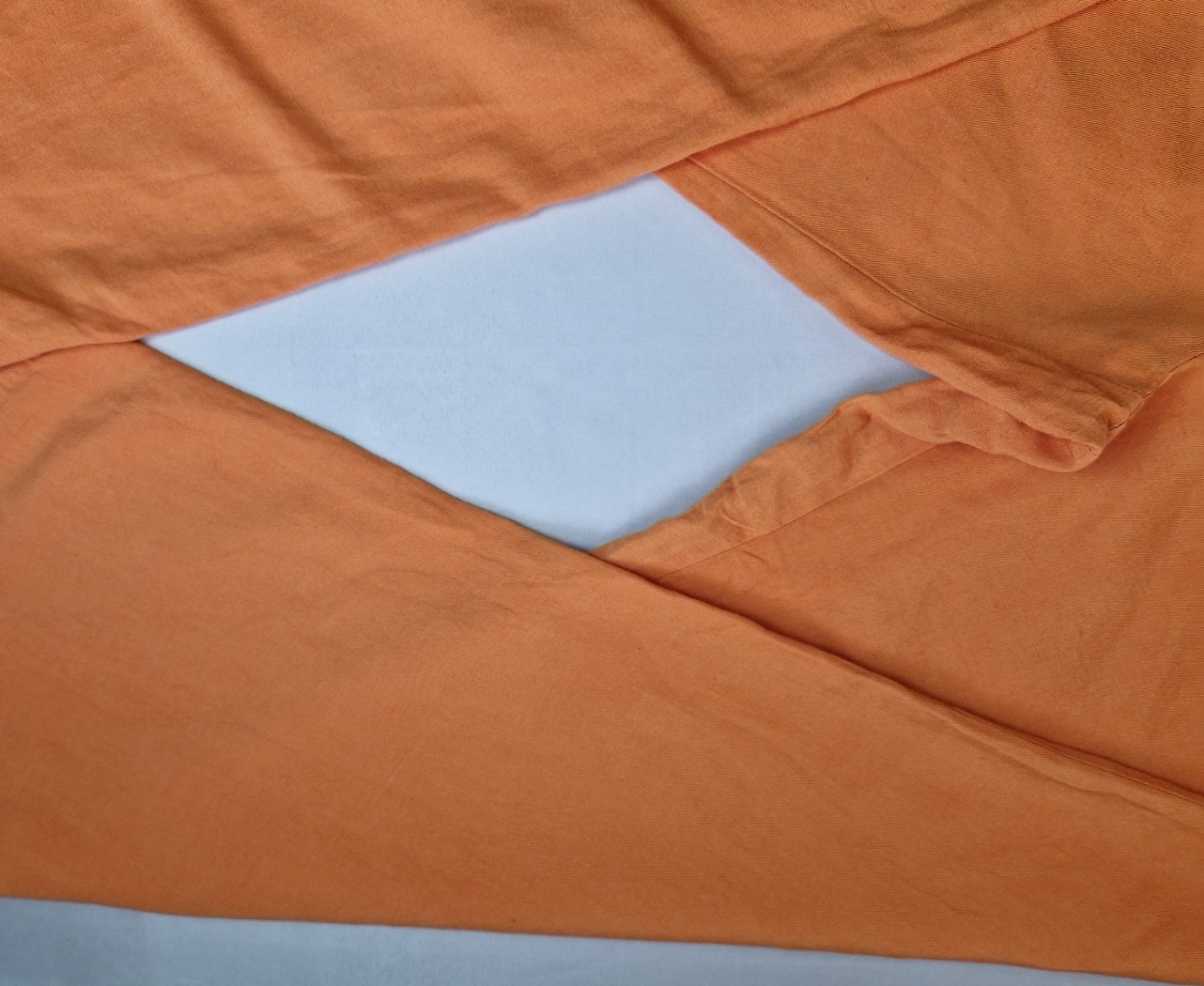 A close-up view of orange wide-leg jogger trousers made from a lightweight linen-blend fabric.