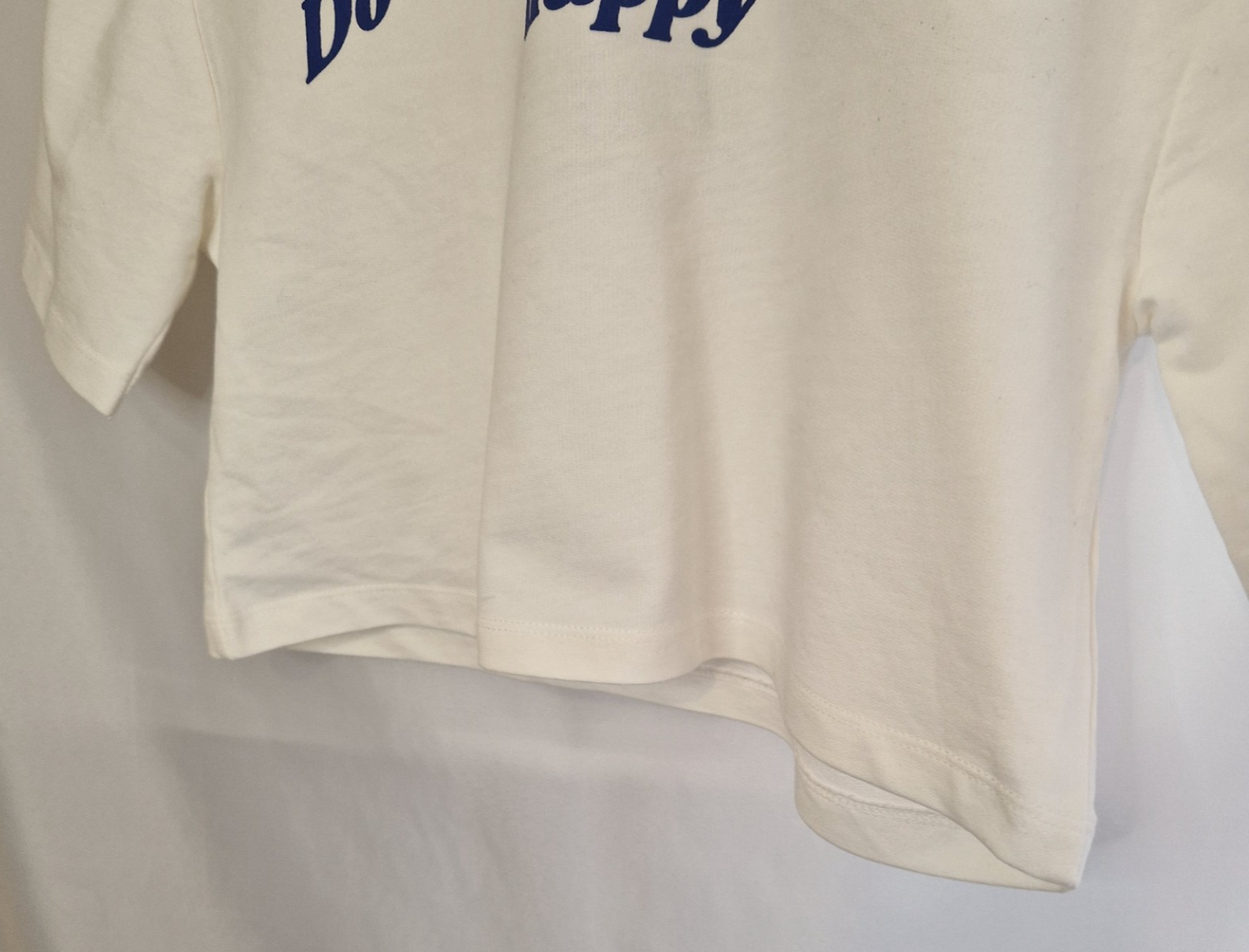 A white short-sleeved toddler t-shirt featuring the blue slogan Do What Makes You Happy.