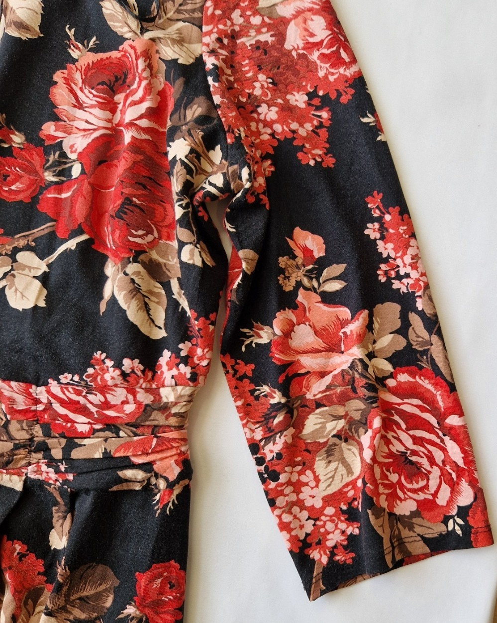 A black fit and flare dress featuring a vibrant red floral print and long flared sleeves.