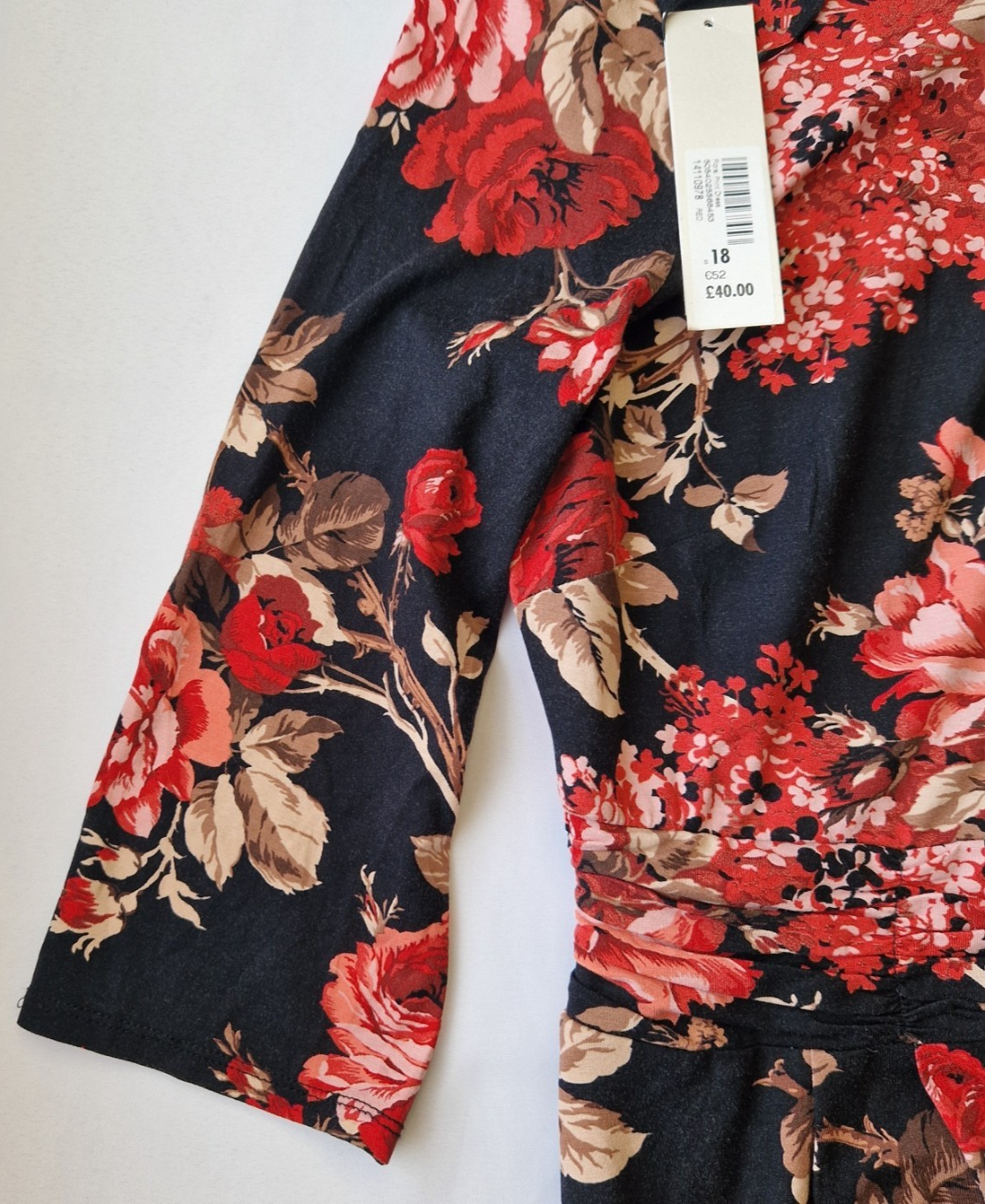 A black fit and flare dress featuring a vibrant red floral print and long flared sleeves.