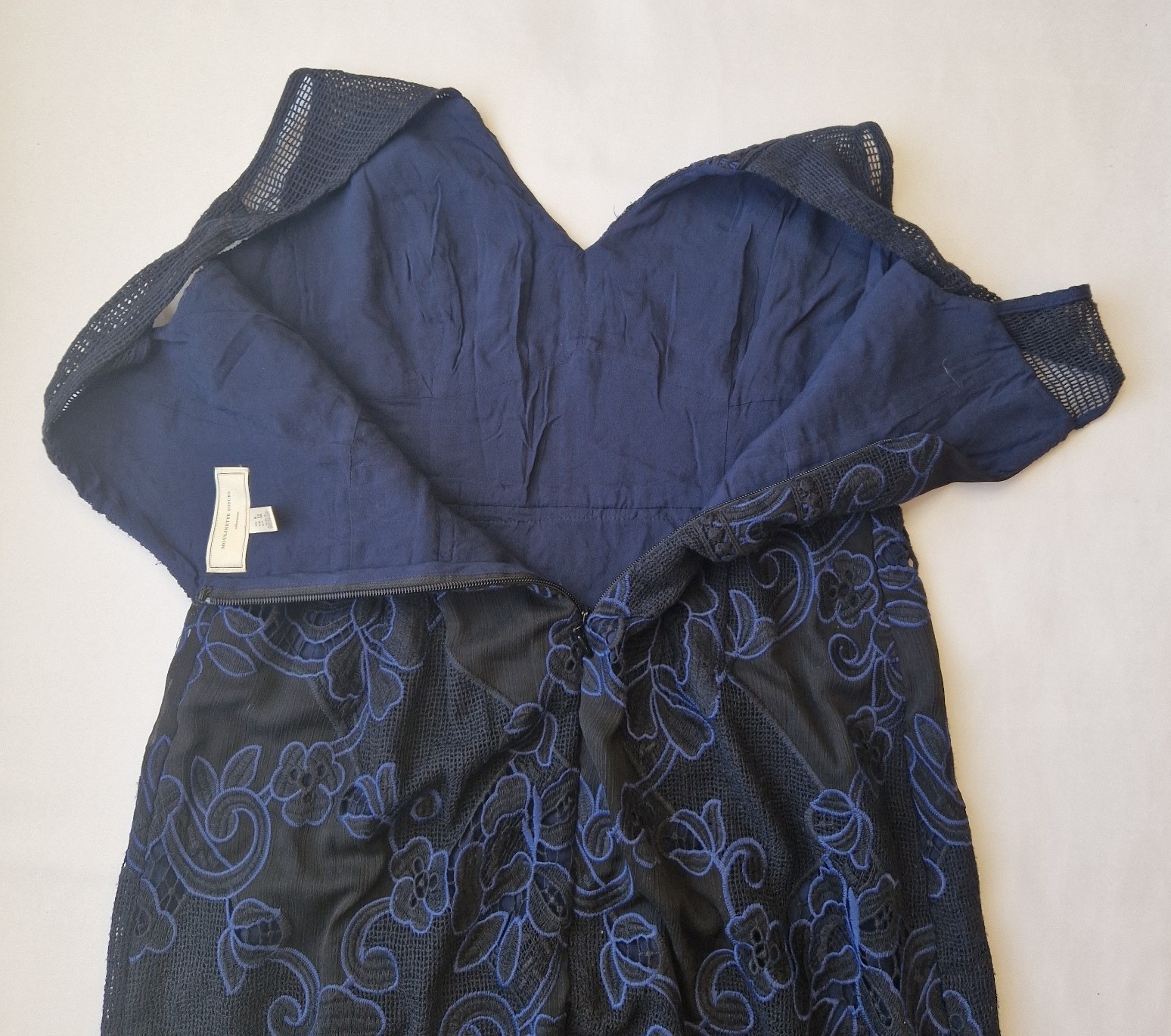 A black and blue sleeveless fit and flare dress featuring intricate floral lace embroidery.