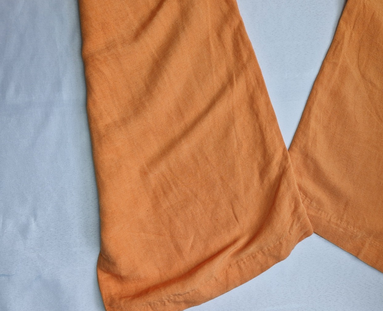 A close-up view of the orange wide-leg hem of H&M linen blend trousers.