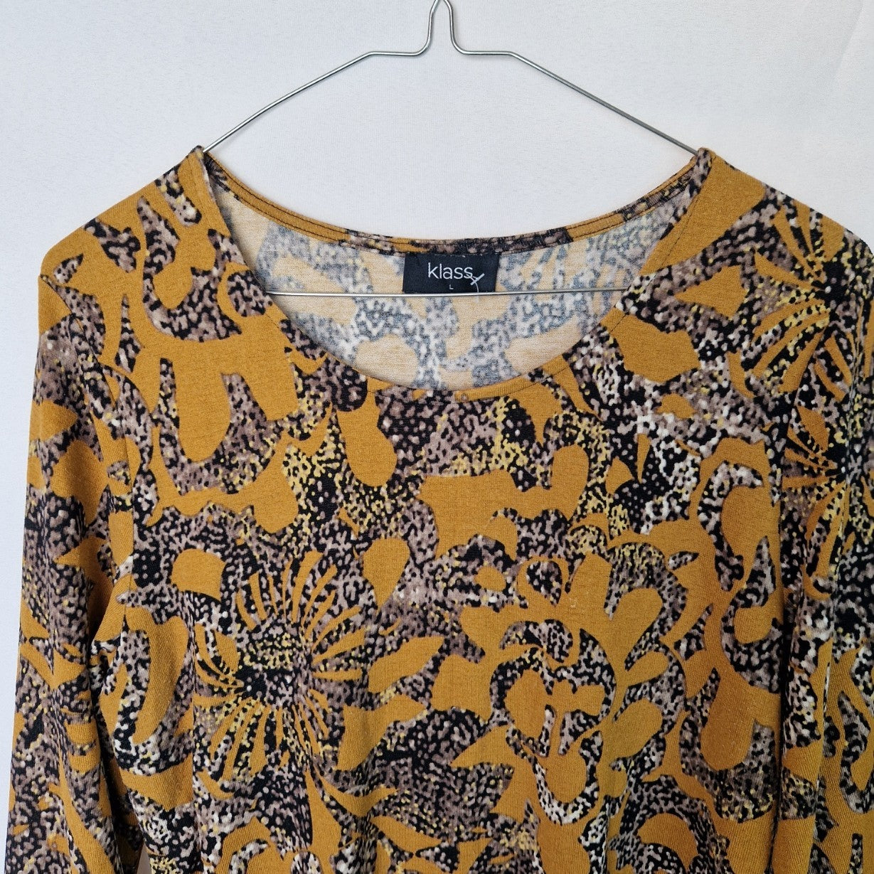 A yellow long-sleeve tunic top by Klass featuring a round neck and a black and grey floral print.
