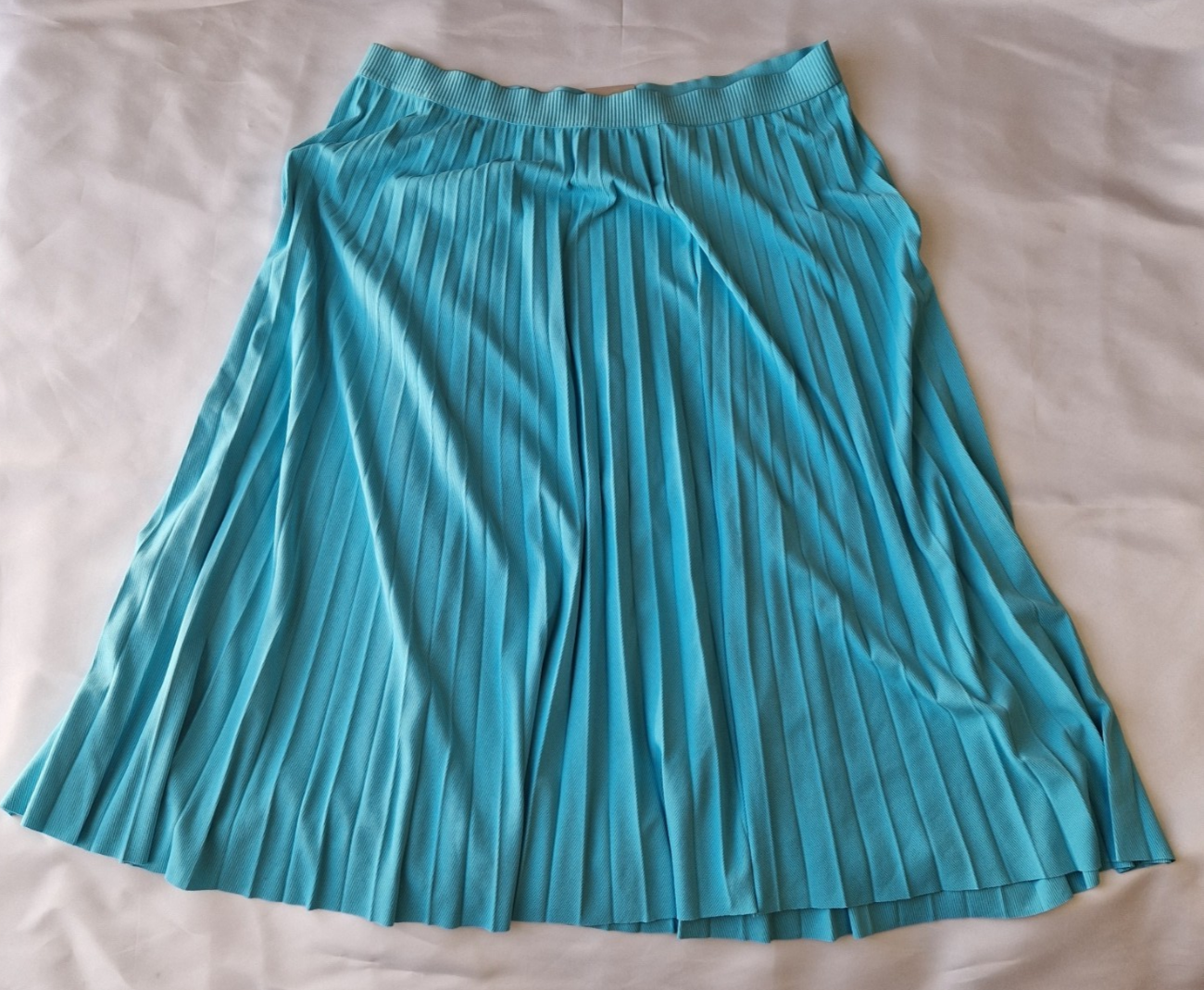 A turquoise pleated midi skirt with an elasticated waistband made from lightweight chiffon fabric.