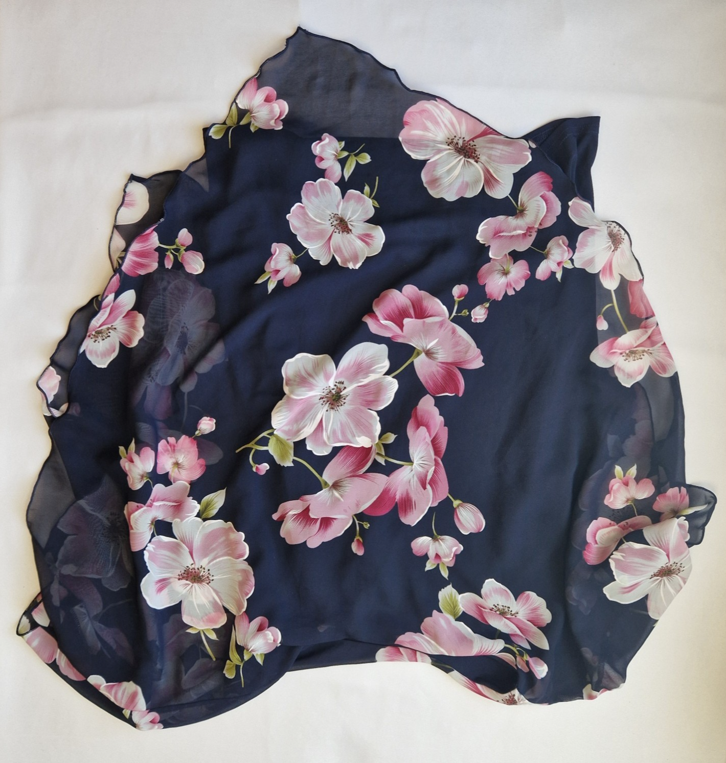 A navy blue sleeveless chiffon blouse featuring a pink floral print and a scalloped hem.