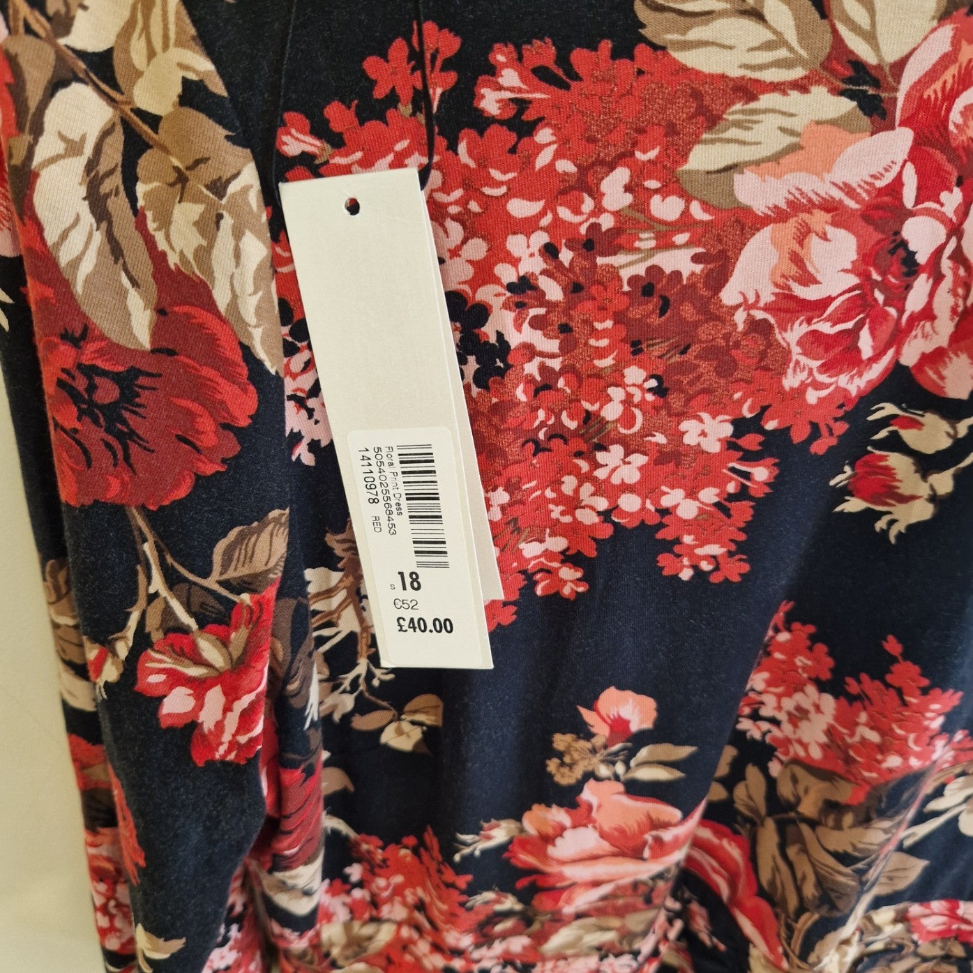 A black fit and flare dress featuring a vibrant red and pink floral print with long sleeves.