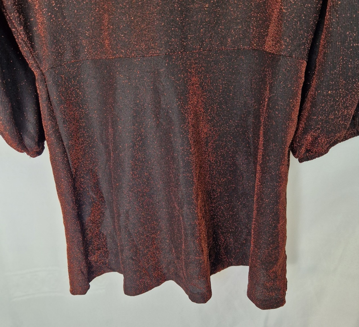 A maroon long-sleeve top with a subtle glitter finish and a draped twist-front design.