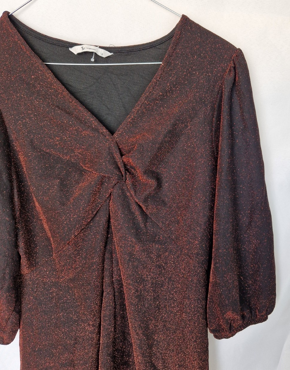 A maroon long-sleeve V-neck top featuring a glitter finish and a twist front detail.