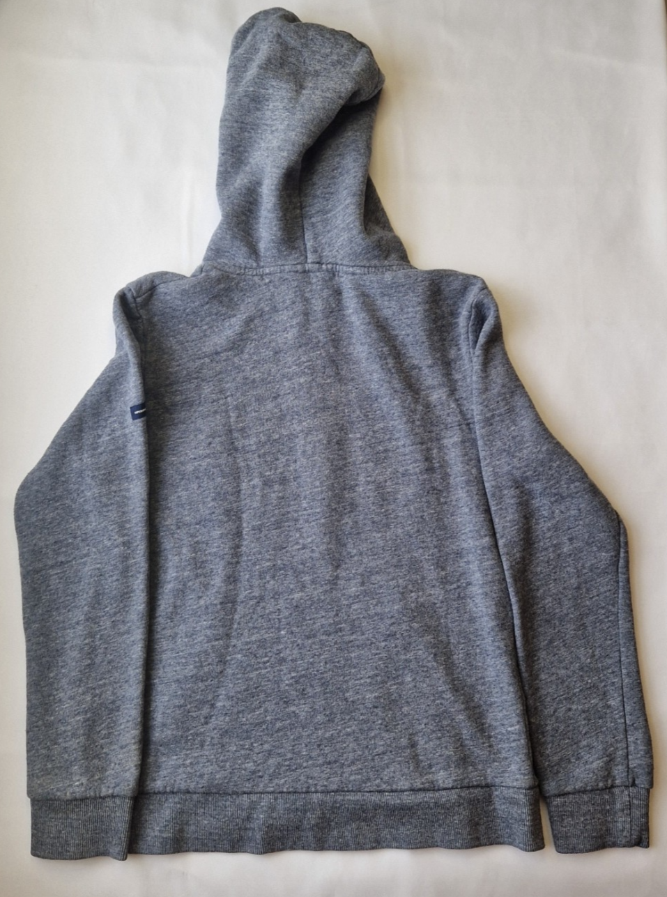 A grey Superdry boys pullover hoodie with a hood and ribbed cuffs shown from the back.