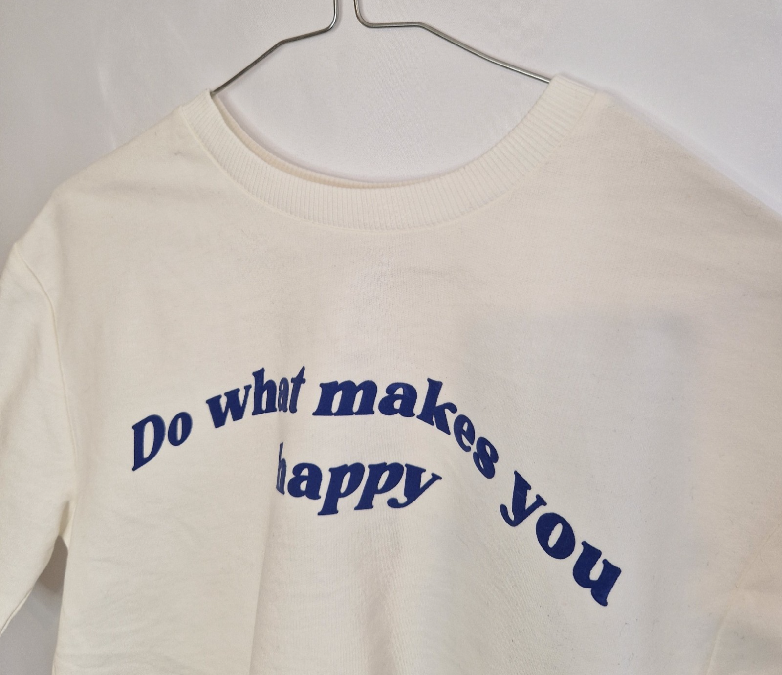 A white short-sleeved toddler t-shirt featuring the blue slogan Do what makes you happy.