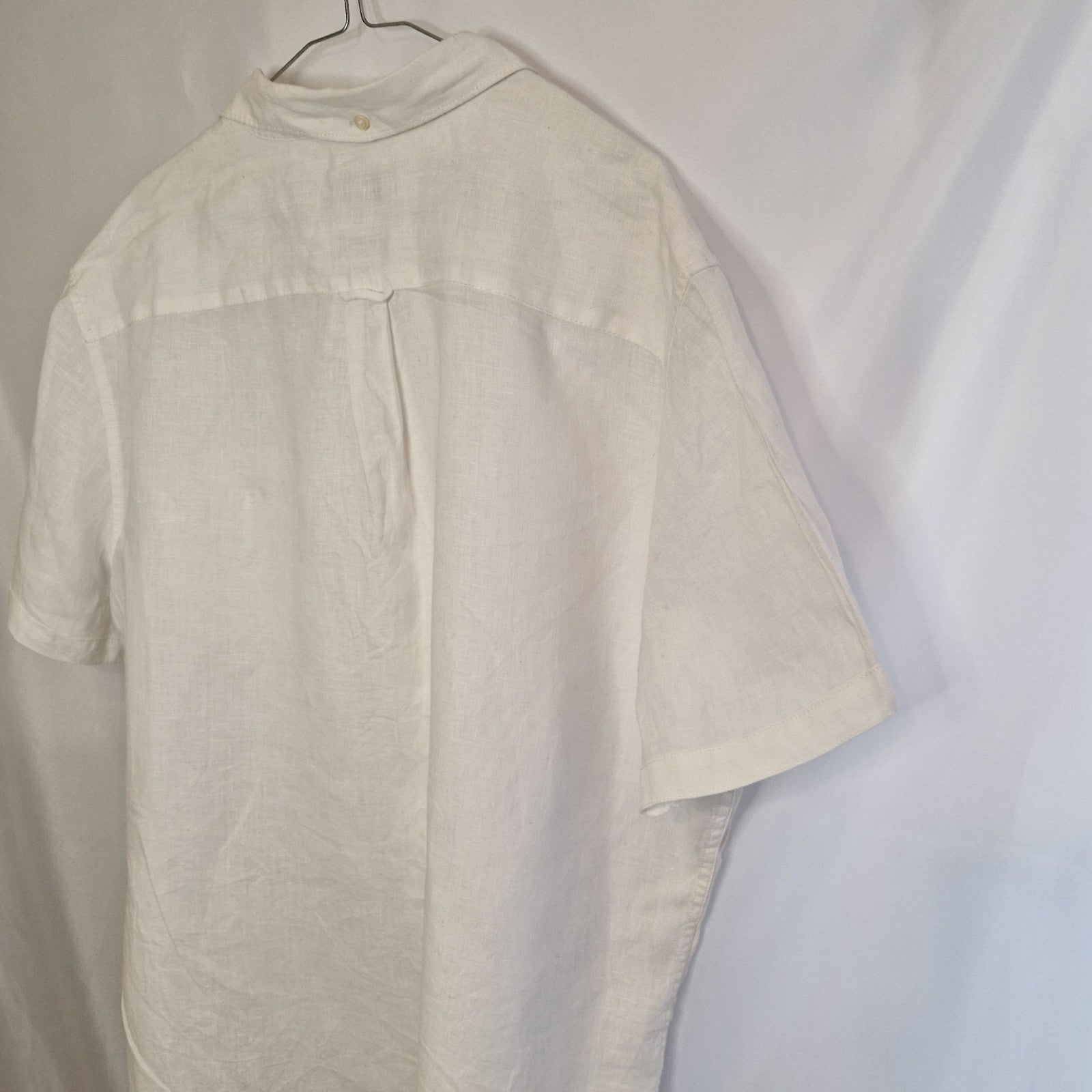 A white short-sleeved button-down shirt with a floral print, shown from the back.