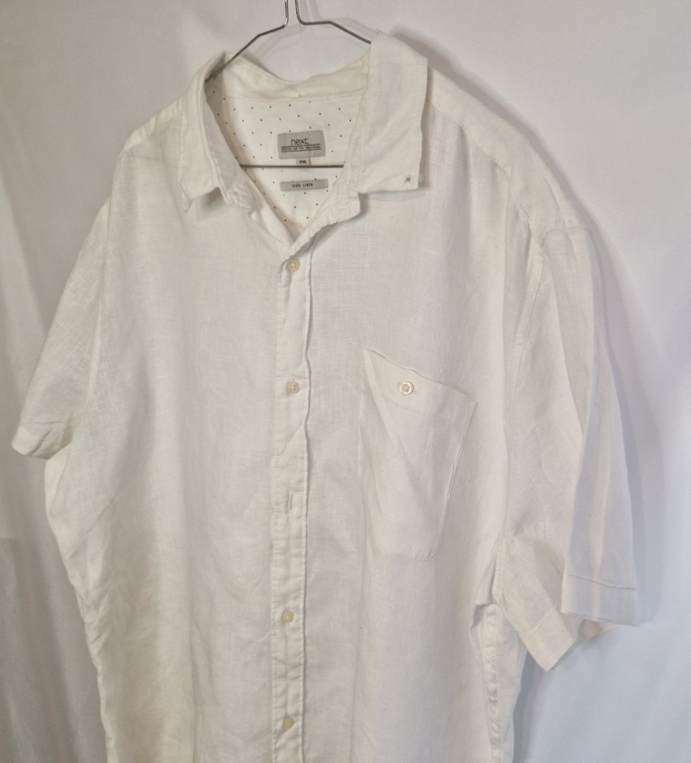 A white short-sleeved button-down shirt by Next with a subtle floral print and chest pocket.