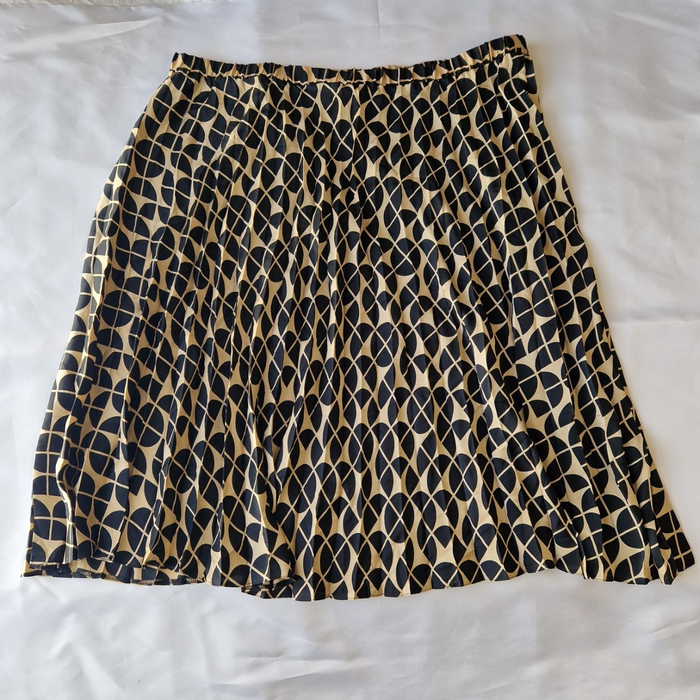 A knee-length, high-rise A-line skirt in a black and metallic gold geometric print.