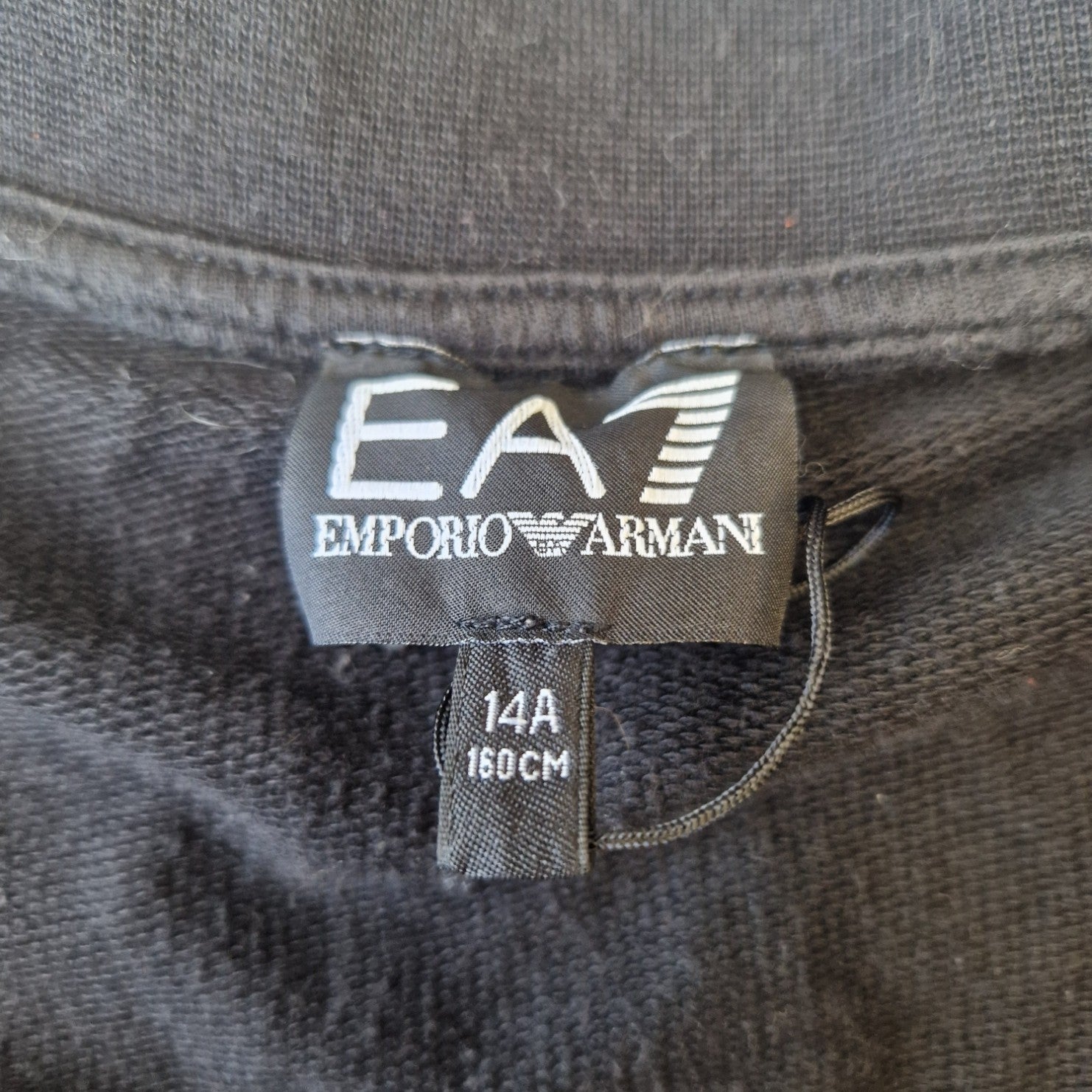 A black EA7 Emporio Armani jacket label showing size 14A and 160cm.