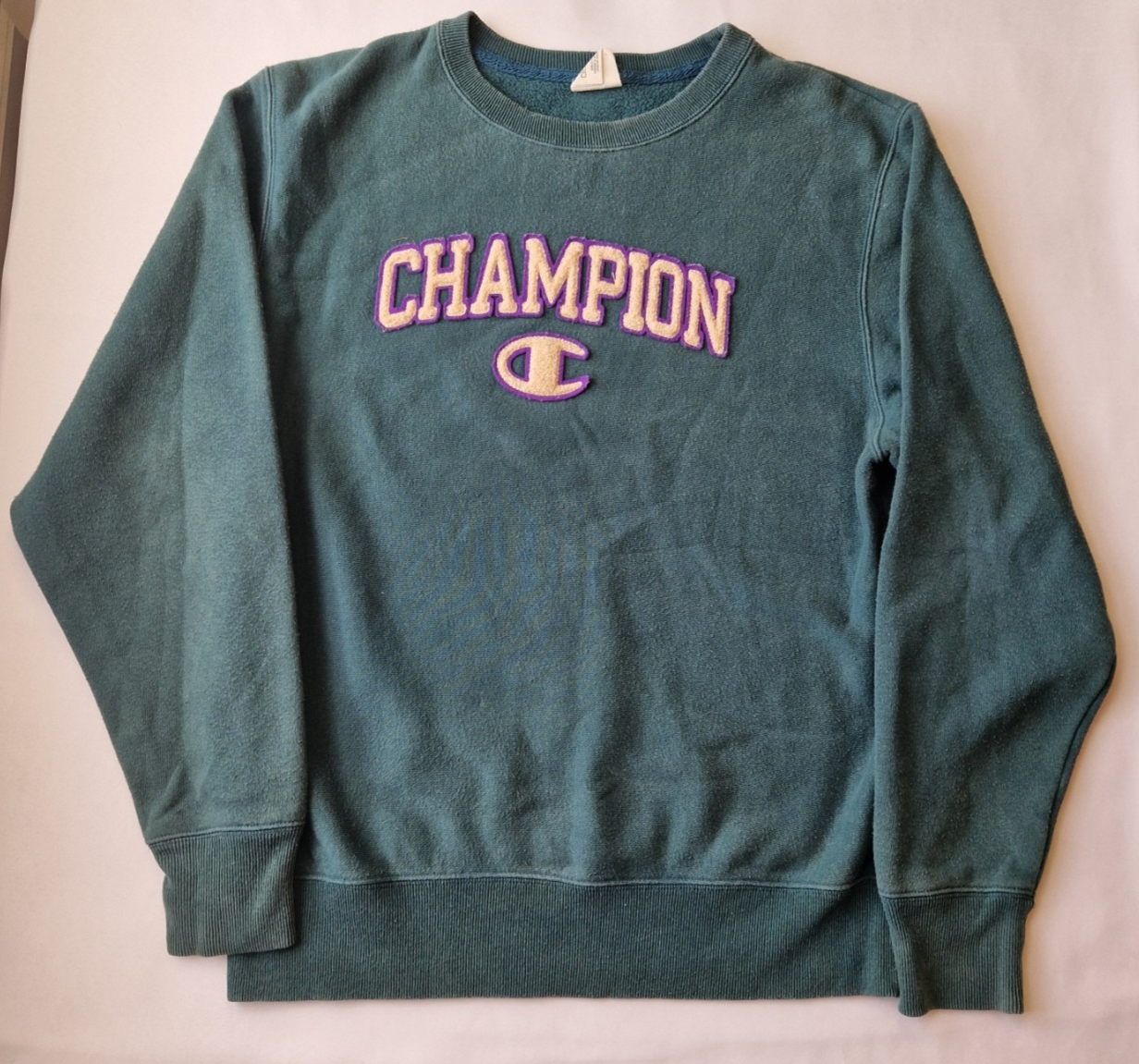 A green Champion cotton pullover sweatshirt with a purple and cream embroidered logo.