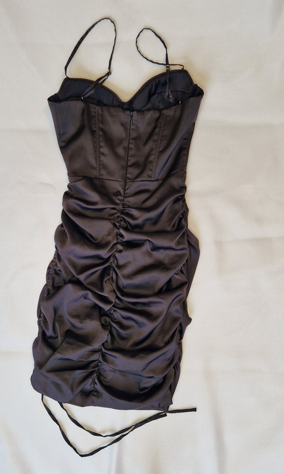 A black satin mini bodycon dress with a ruched finish and thin spaghetti straps.