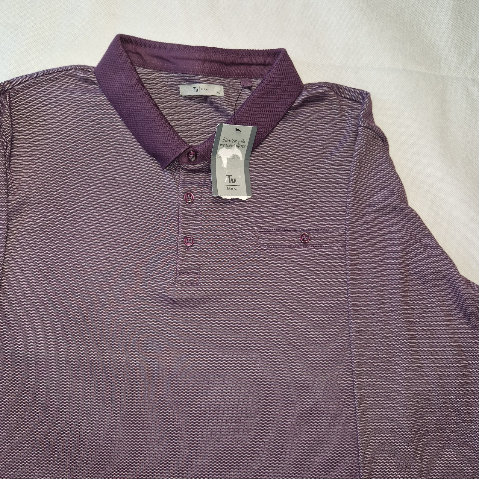 A purple Tu Man polo shirt with a textured collar, button placket, and a small chest pocket.
