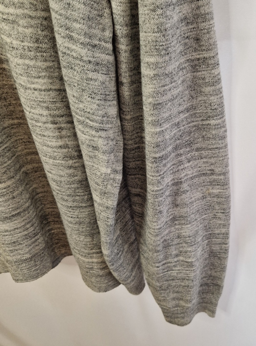 A grey long-sleeve knit pullover with a textured marl finish hanging against a white background.
