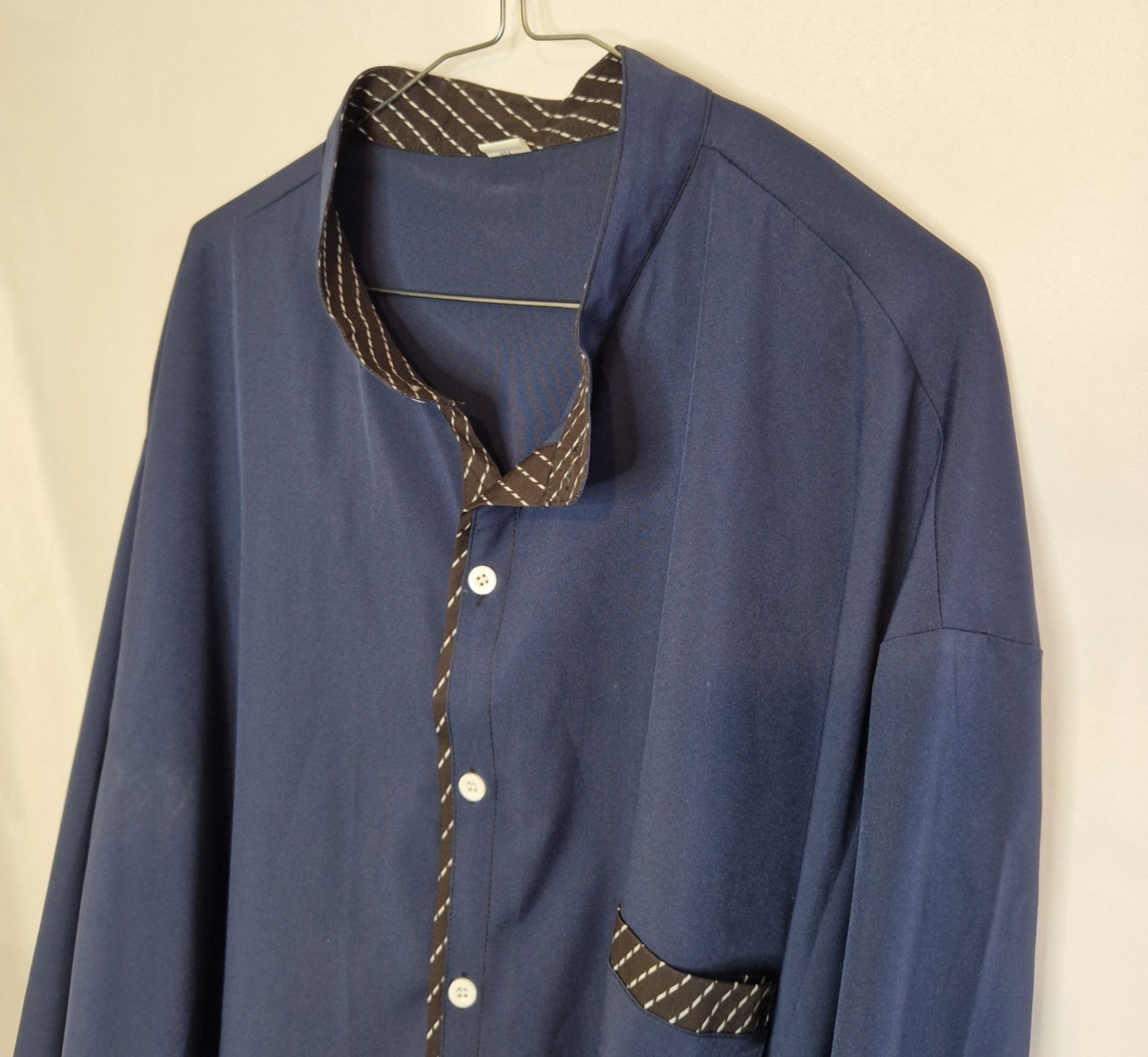 A blue long-sleeve satin shirt with a mandarin collar and patterned contrast trim.