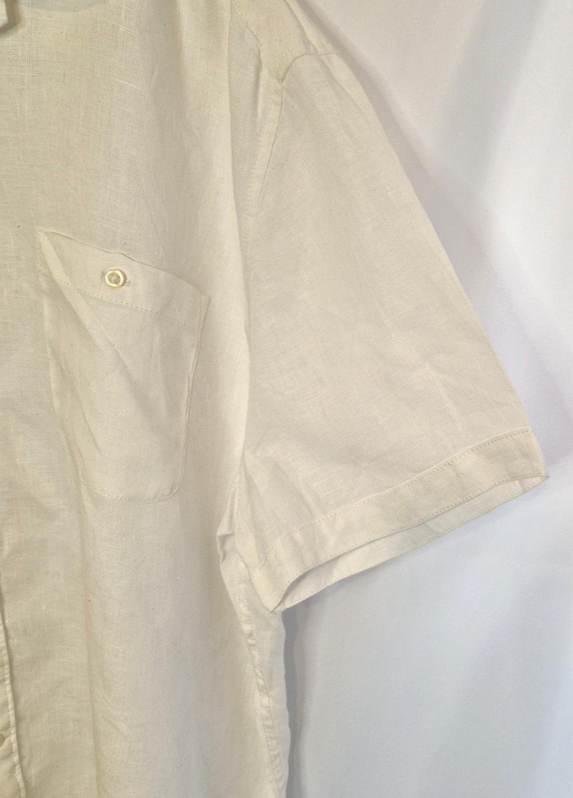 A white short-sleeved button-down shirt with a subtle floral print and a chest pocket.