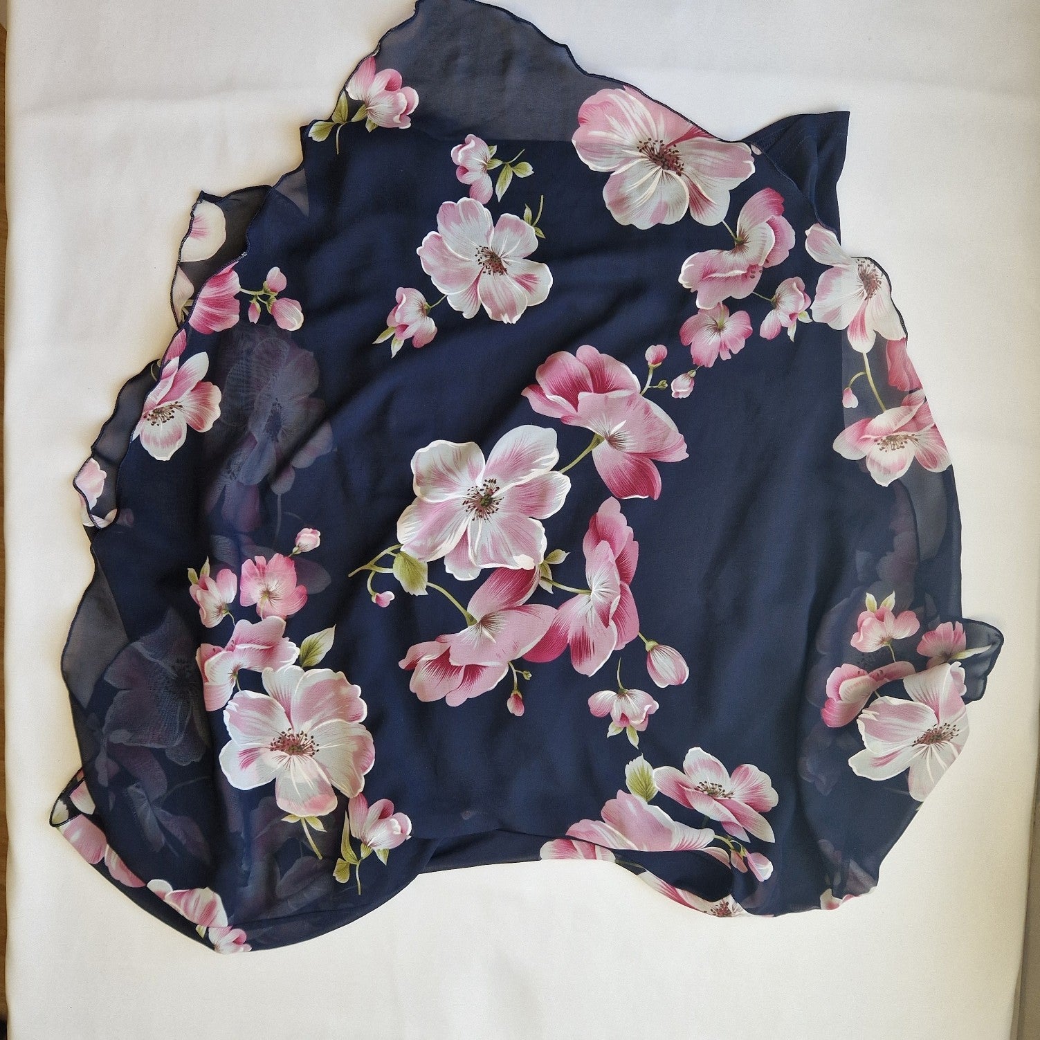 A navy blue sleeveless chiffon blouse featuring a pink floral print and a scalloped hem.