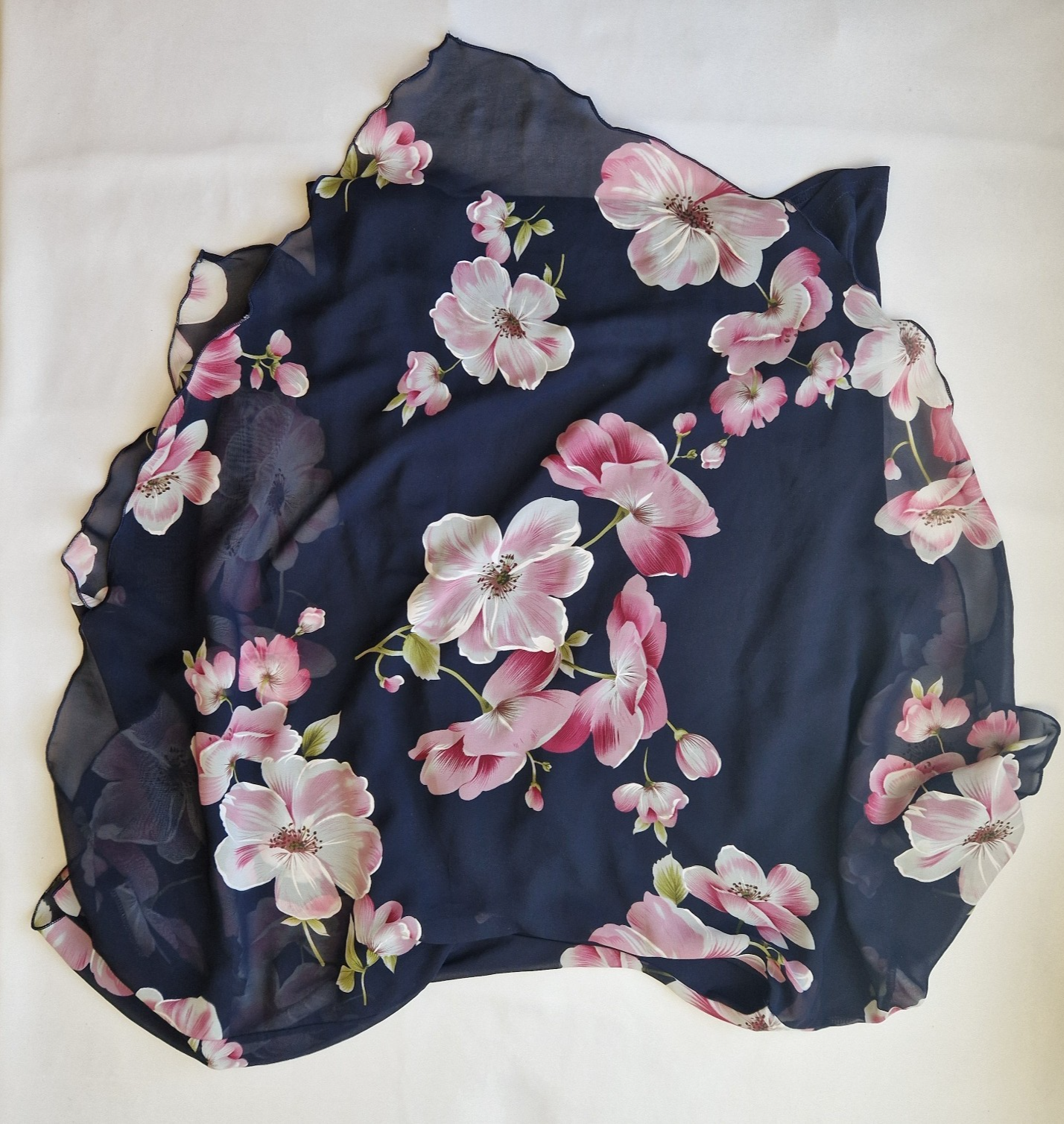 A navy blue sleeveless chiffon blouse featuring a pink floral pattern and a scalloped hem.