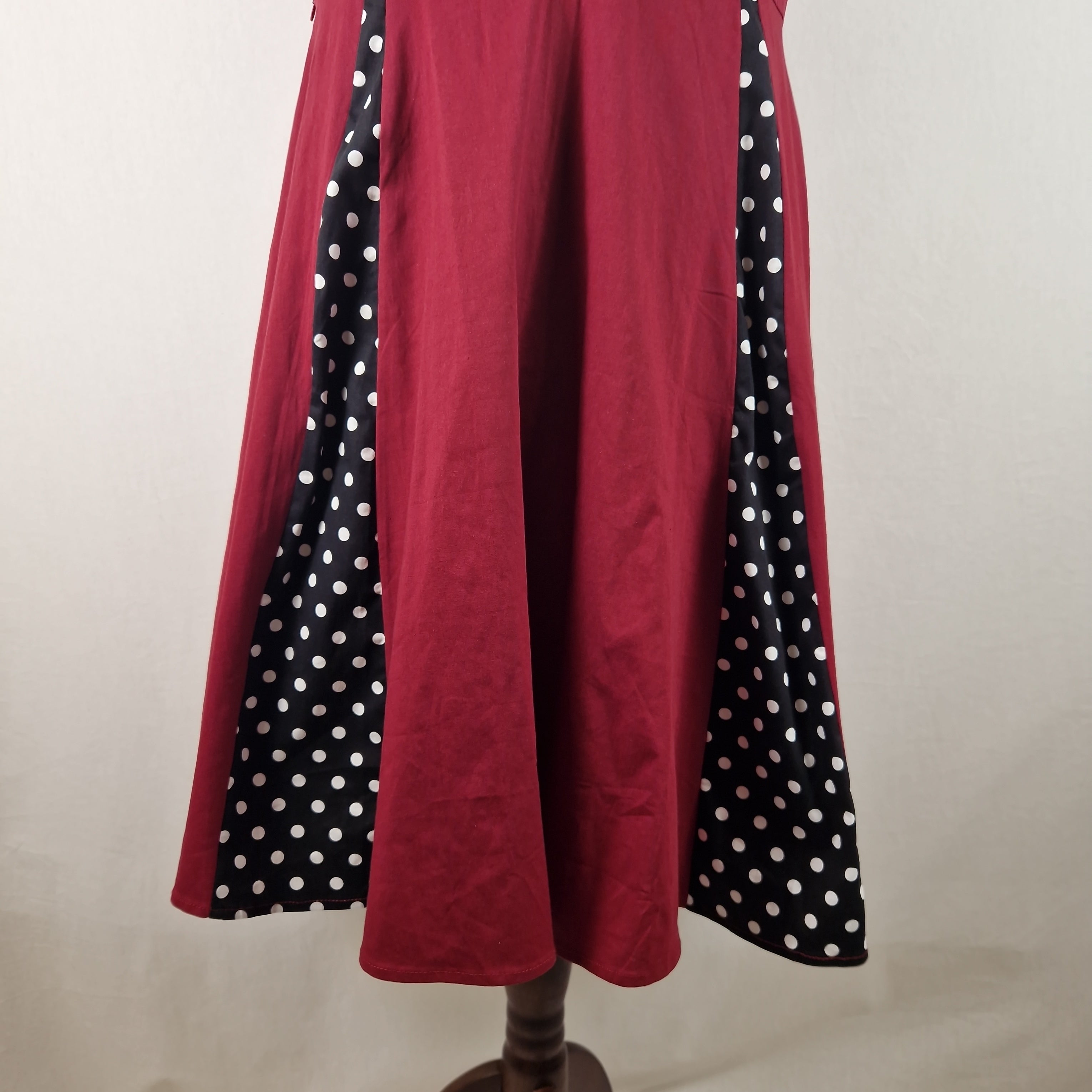 Red skirt with black and white polka dot trim on a mannequin against a plain background