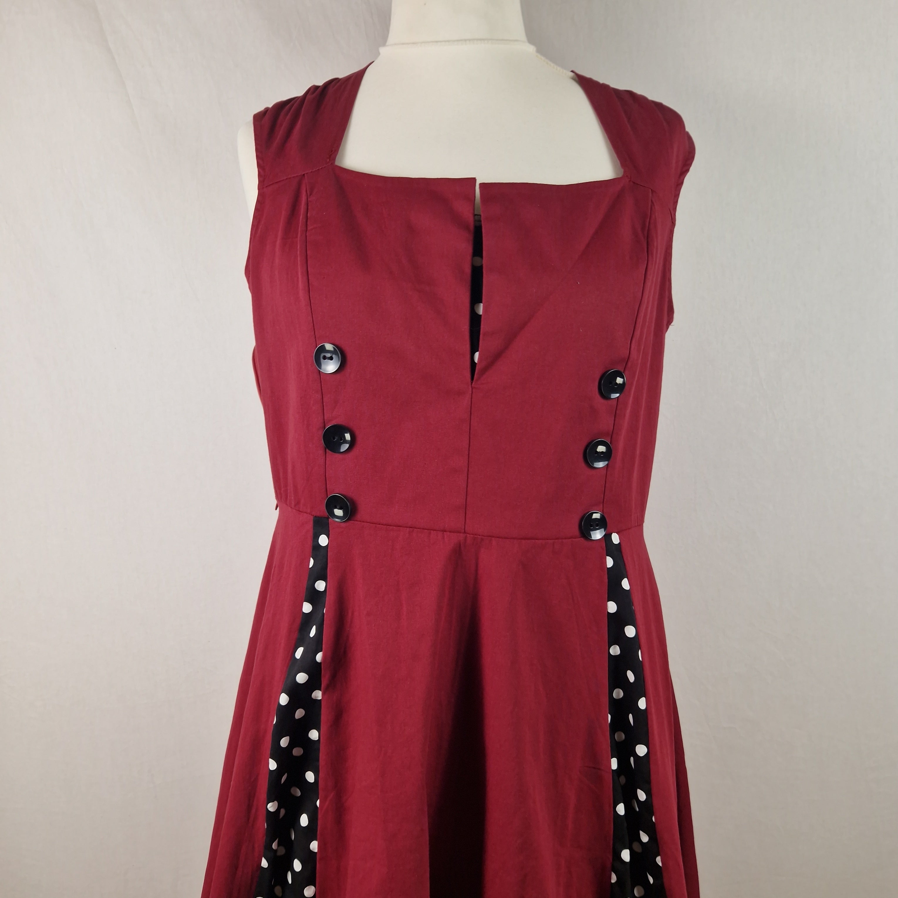 Red dress with black buttons and polka dot trim on a mannequin against a plain background
