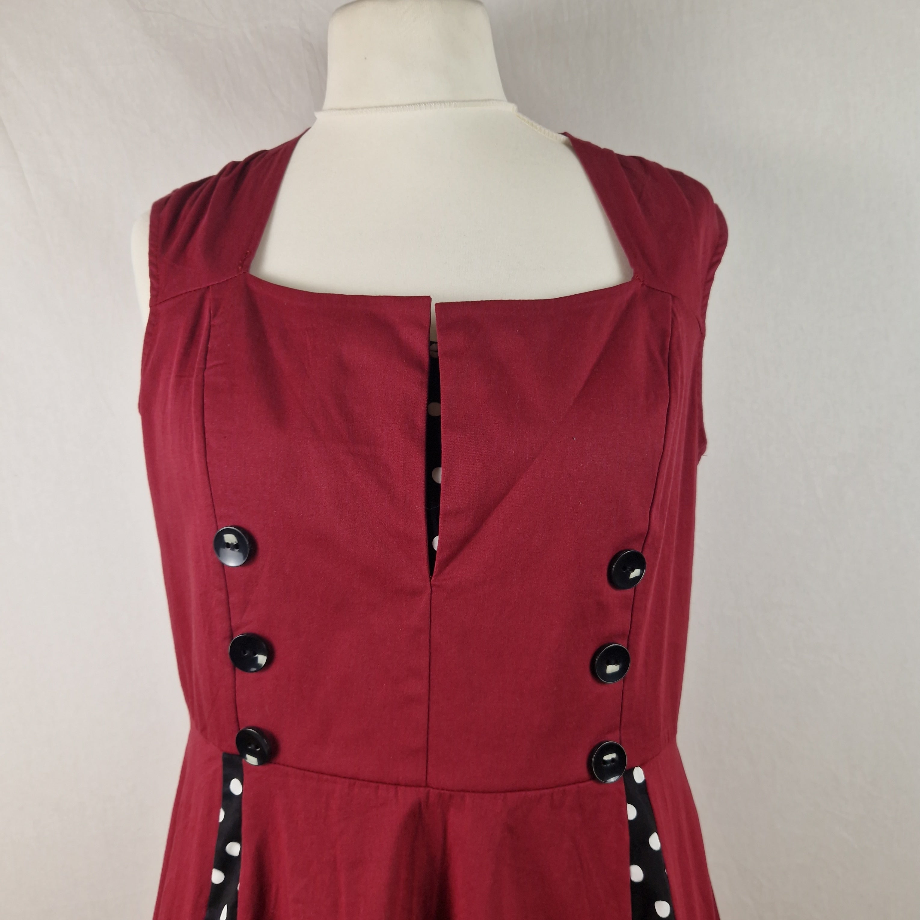Red dress with black buttons on a mannequin against a plain background