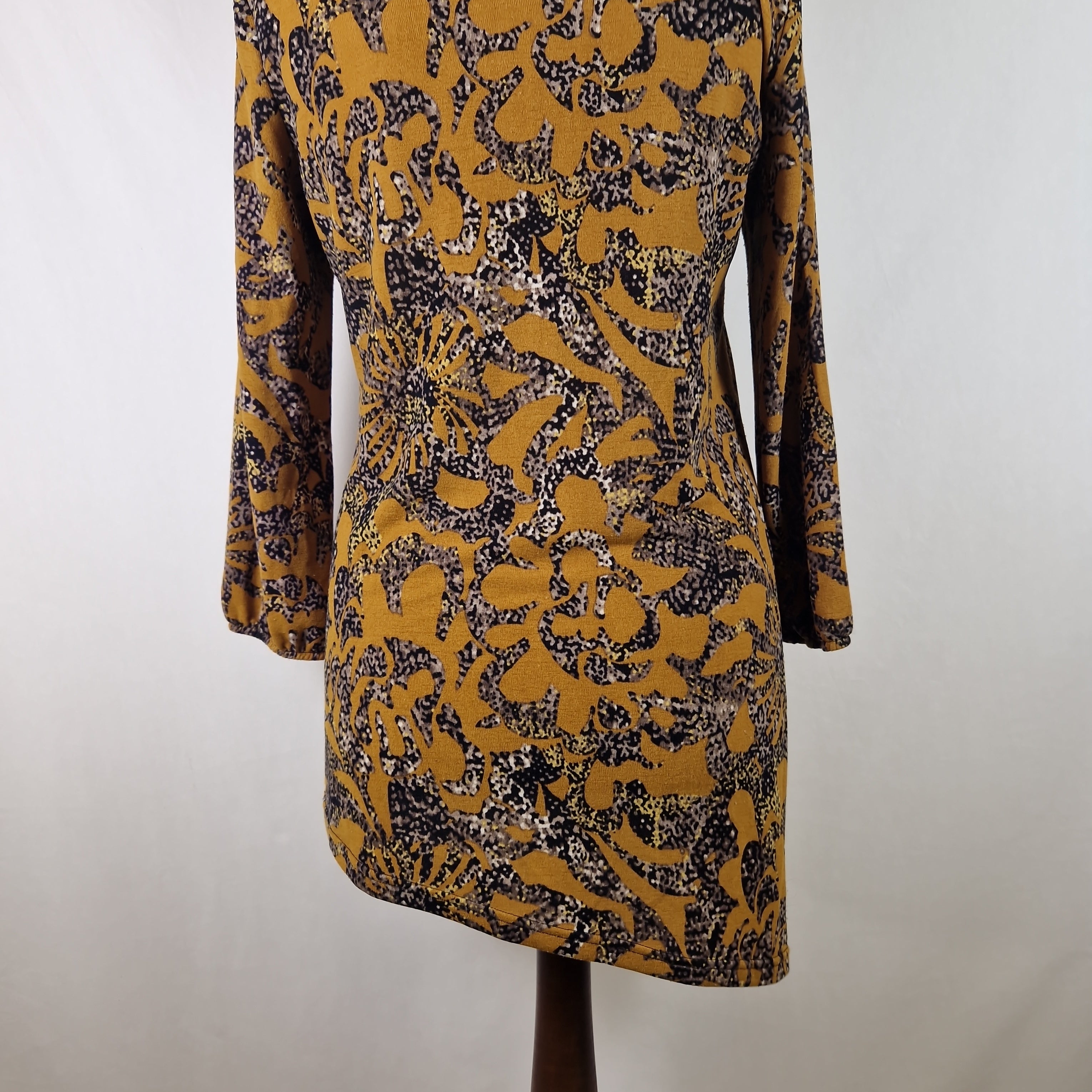 Yellow and black patterned dress on a mannequin against a plain background