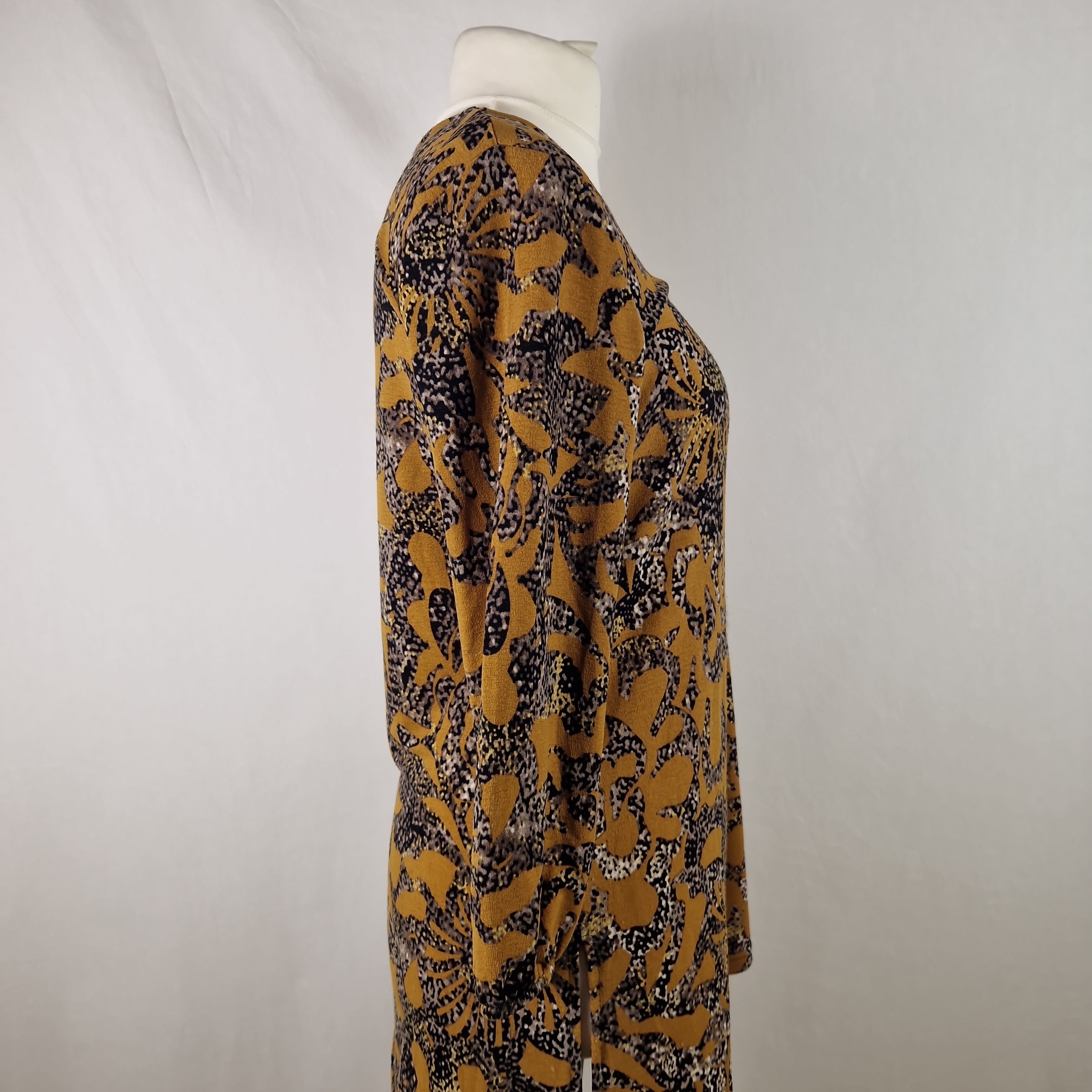 Mannequin wearing a patterned dress with long sleeves on a plain background