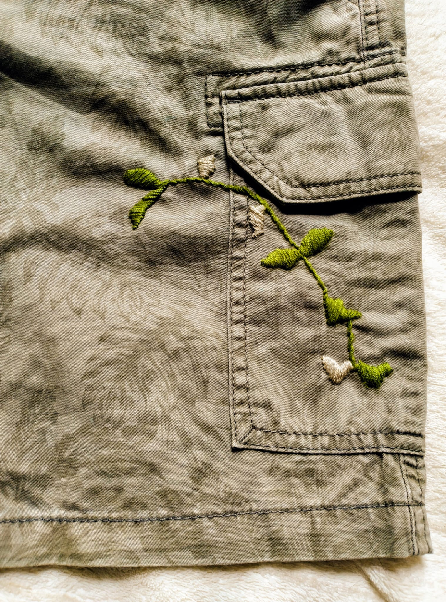 Translation missing: en.Close-up of a green embroidered design on beige fabric