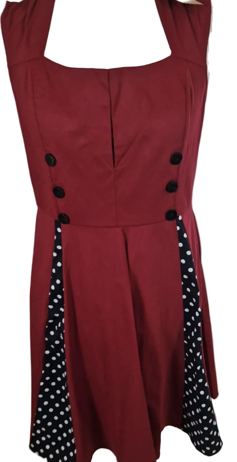 A sleeveless red A-line midi dress featuring black buttons and black polka dot side panels.