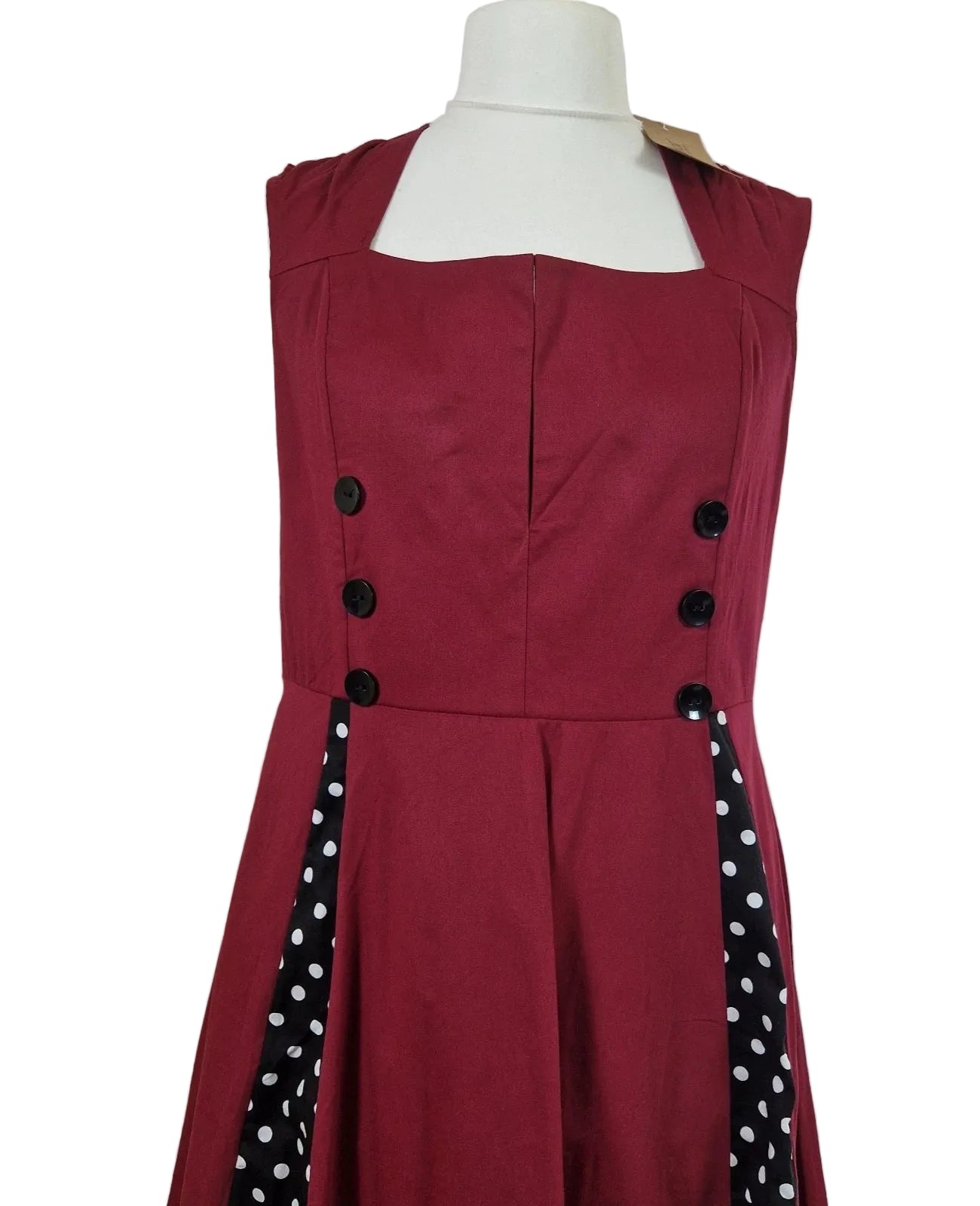 A sleeveless red A-line midi dress featuring a square neckline and black polka dot side panels.
