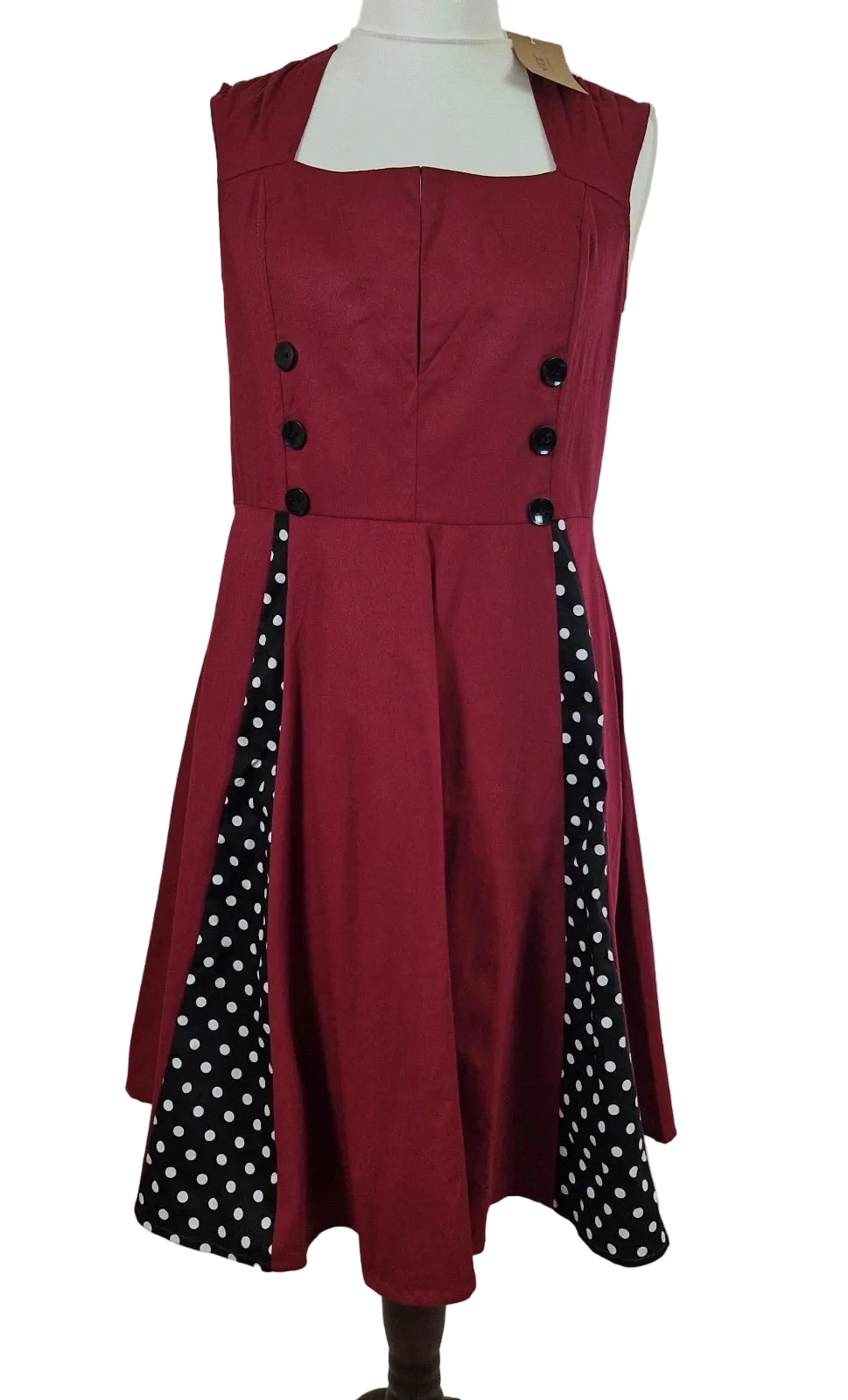 A sleeveless red A-line midi dress featuring black polka dot side panels and button accents.