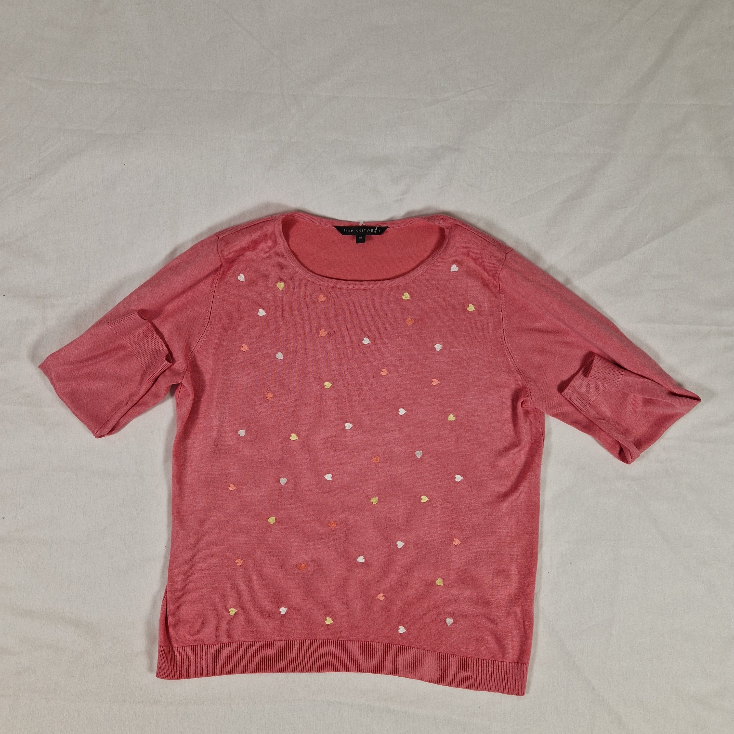Pink long-sleeve shirt with heart patterns on a light gray background