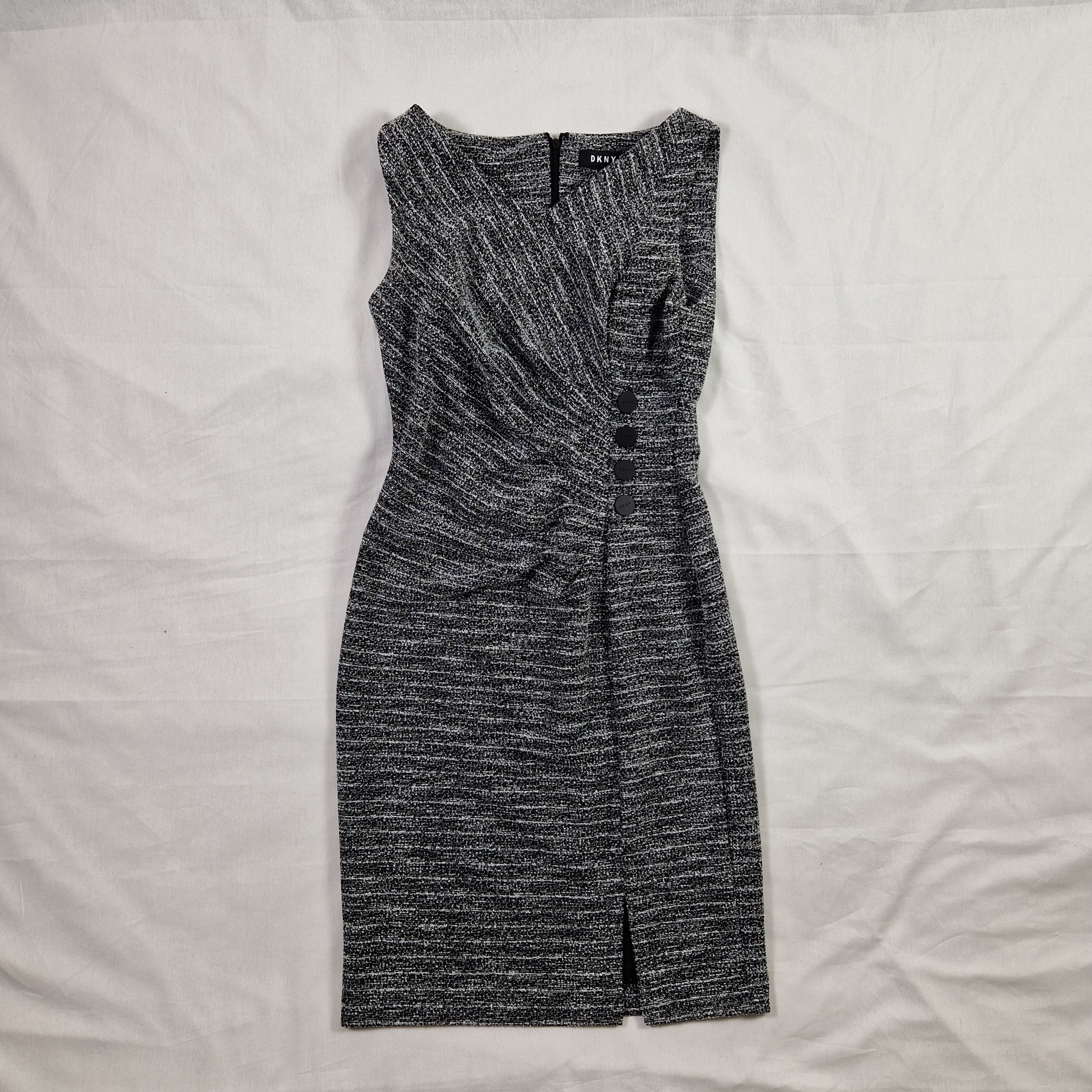 Folded gray pants on a white bed