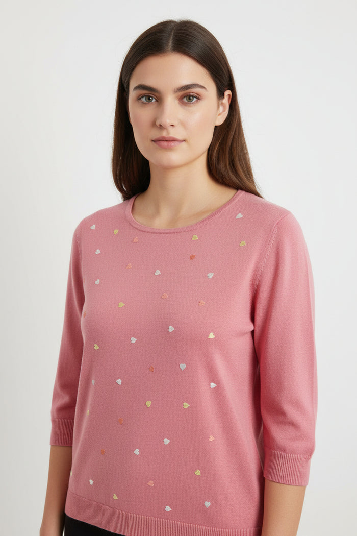 Pink sweater with small heart patterns on a light gray background