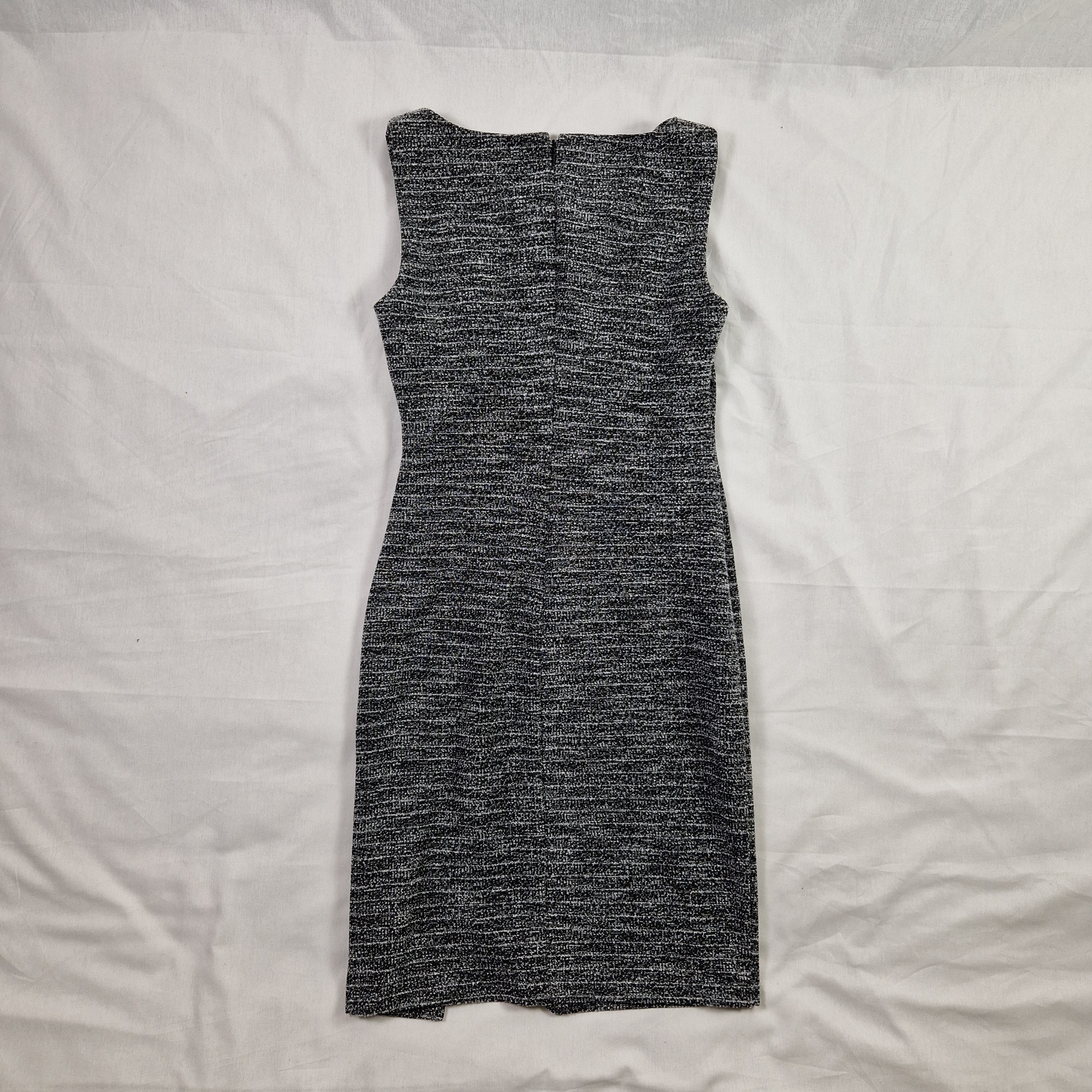Folded gray sweater on a white bed